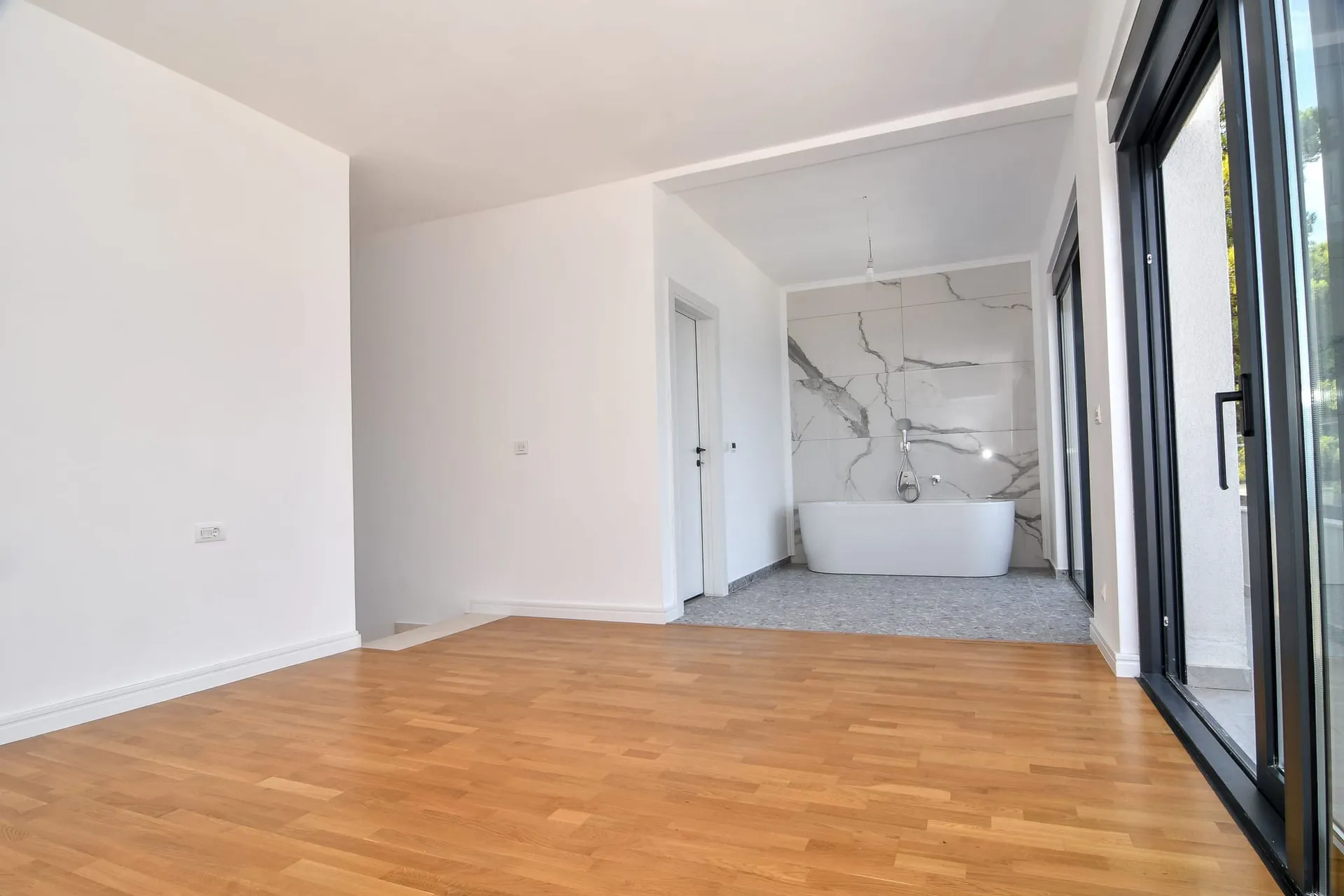 Chambre moderne avec baignoire îlot et baies vitrées panoramiques dans une villa à Budva, Monténégro.