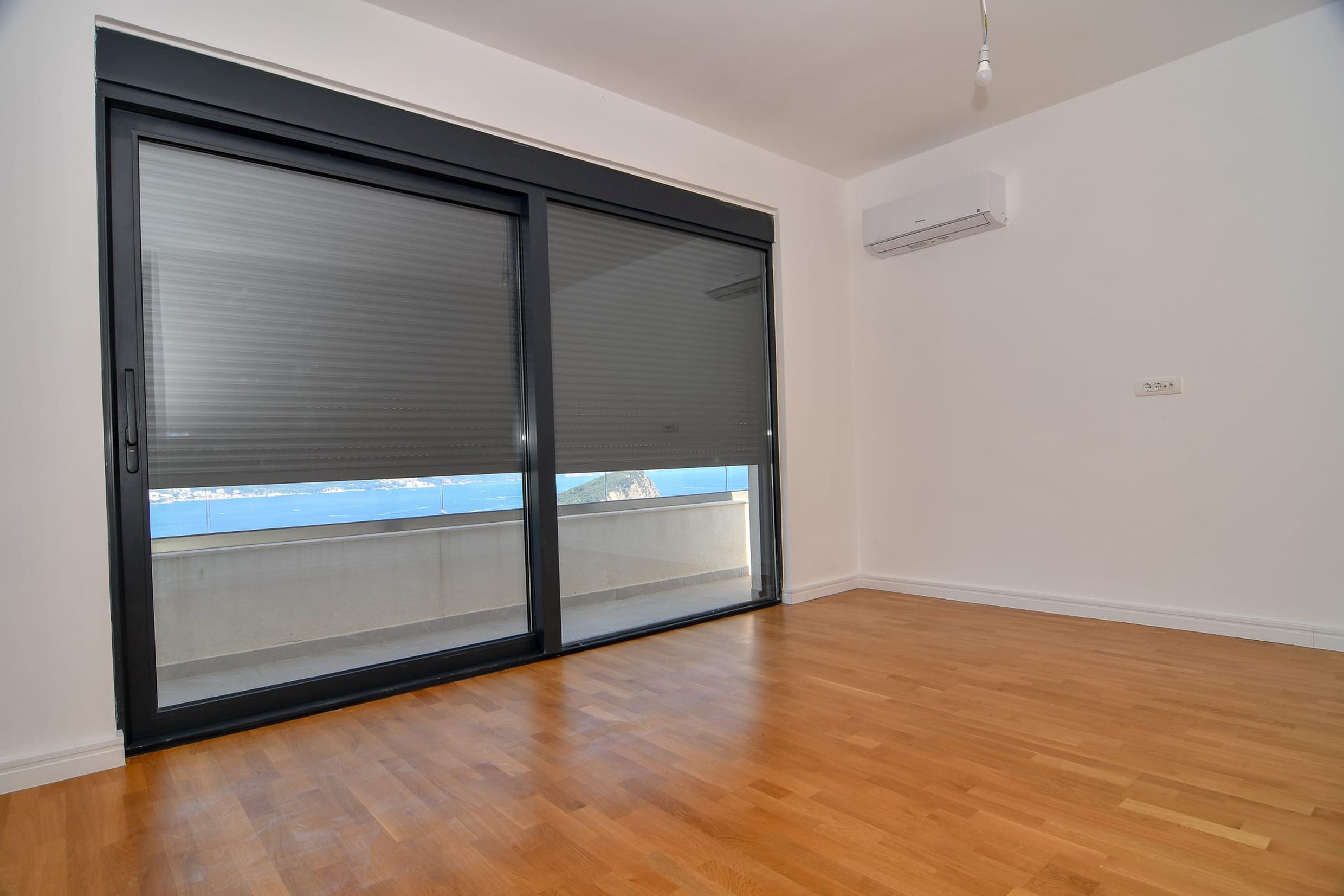 Helles Wohnzimmer mit Panoramafenster, Meerblick und Terrasse in einer Villa in Budva, Montenegro. Parkett und Klimaanlage.