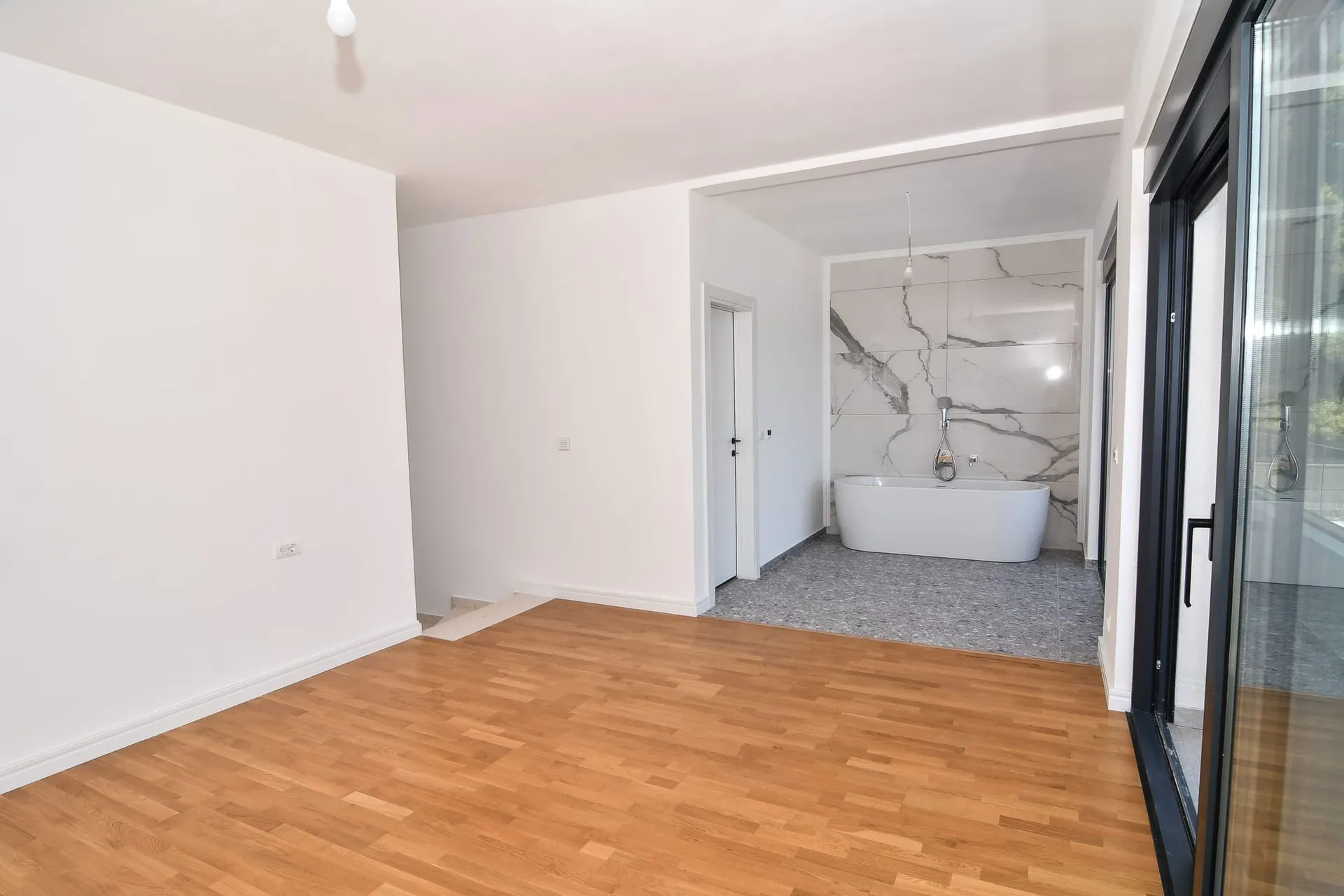 Chambre avec salle de bain dans une villa moderne à Budva, Monténégro : parquet, baies vitrées panoramiques et finitions en marbre.