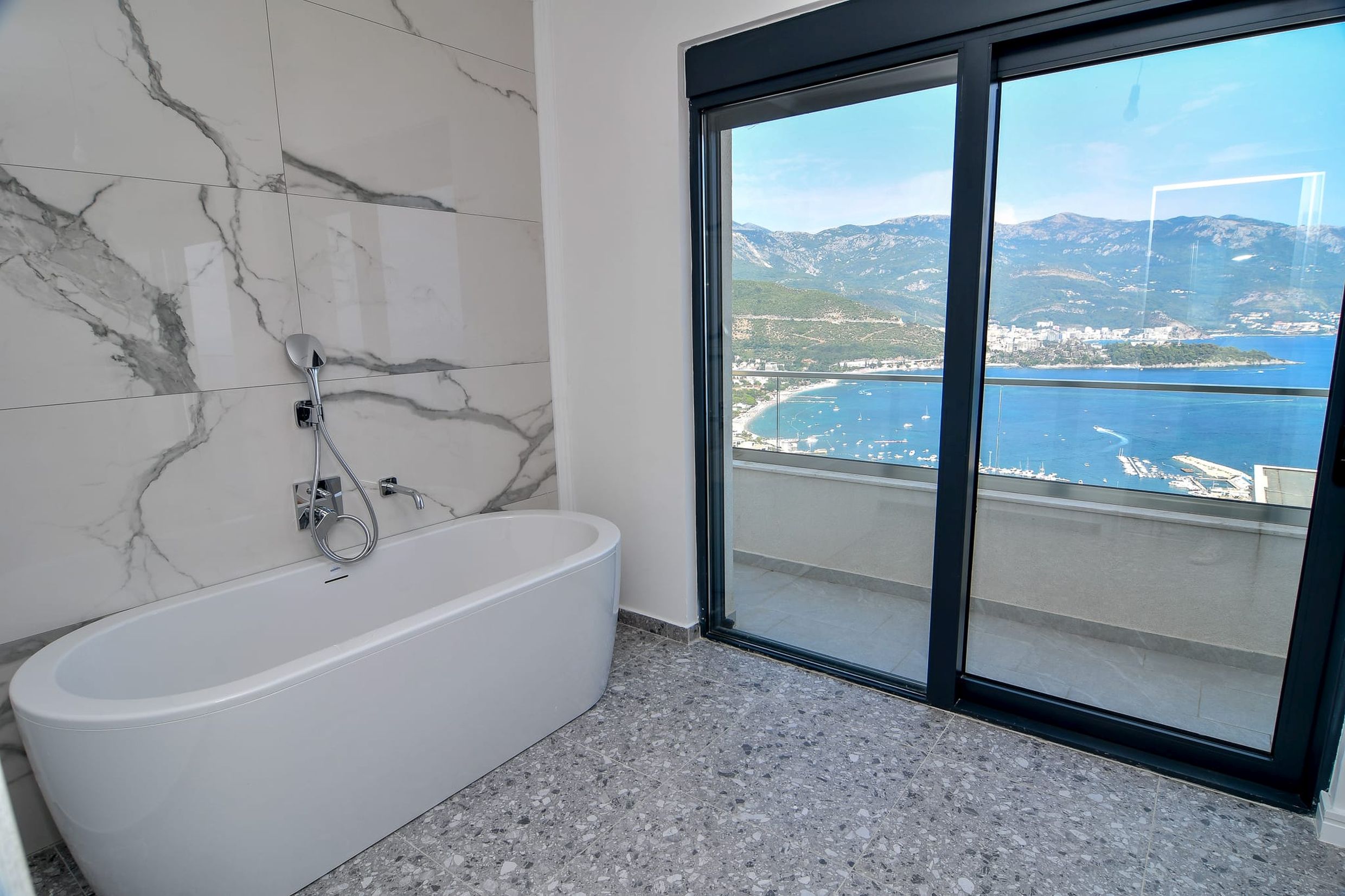 Badezimmer mit Panoramablick auf das Meer und die Berge in der Villa Budva, Montenegro: moderne Ausstattung und stilvolle Badewanne.