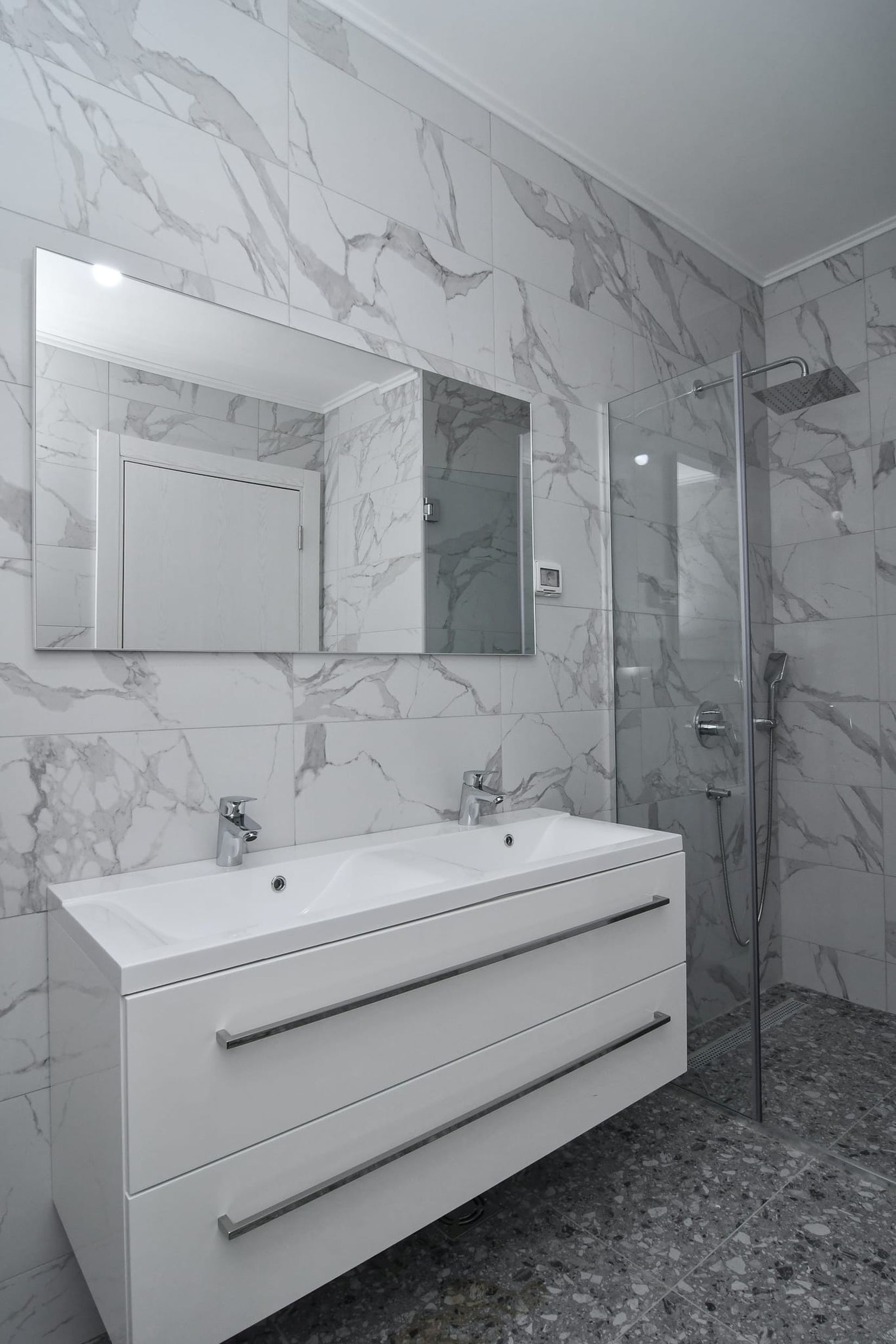Modernes Badezimmer mit Duschkabine und Doppelwaschbecken in einer Villa in Budva, Montenegro, in Marmoroptik.