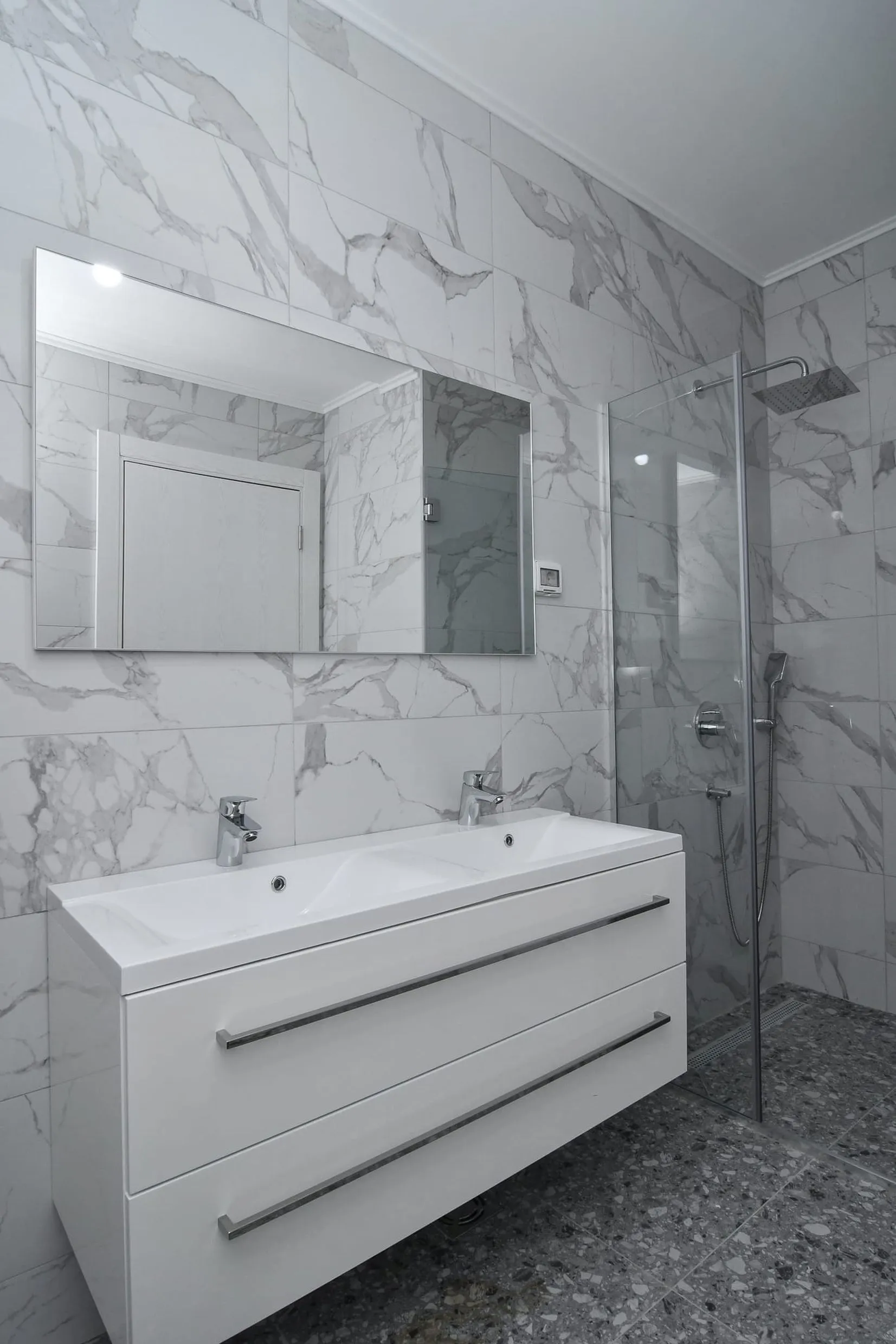 Salle de bains moderne avec cabine de douche et double vasque dans une villa à Budva, Monténégro, finition effet marbre.