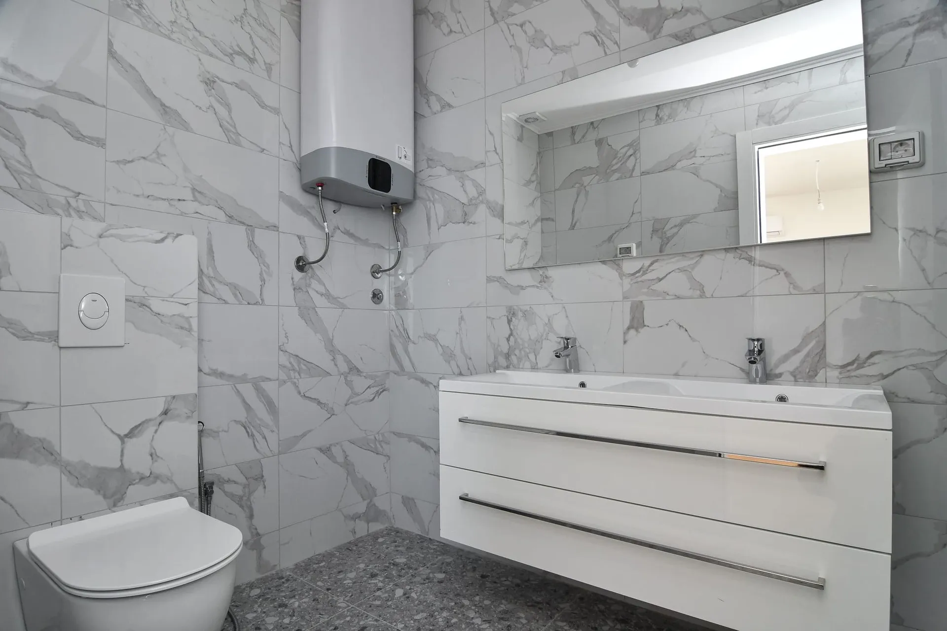 Salle de bains moderne avec finition effet marbre dans une villa, Budva, Monténégro : meuble vasque et chauffe-eau.