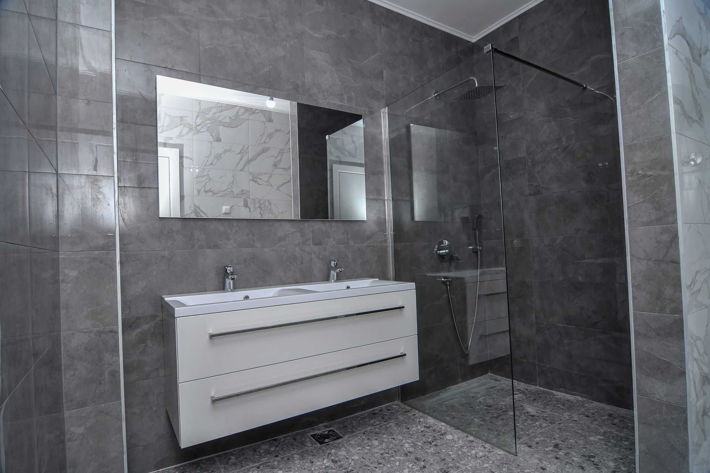 Modernes Badezimmer mit Duschkabine und grauen Fliesen in einer Villa in Budva, Montenegro.