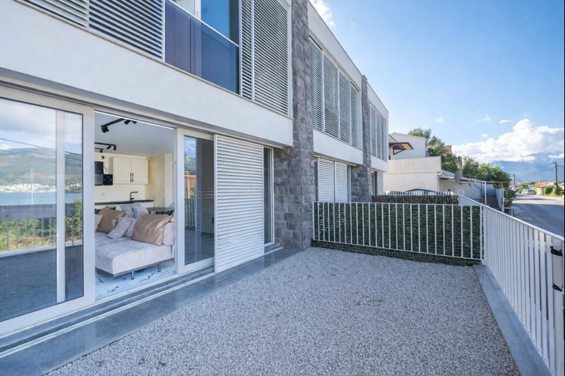 Modern townhouse in Luštica, Montenegro: spacious terrace with panoramic glazing, sea view, and a bright living room ...