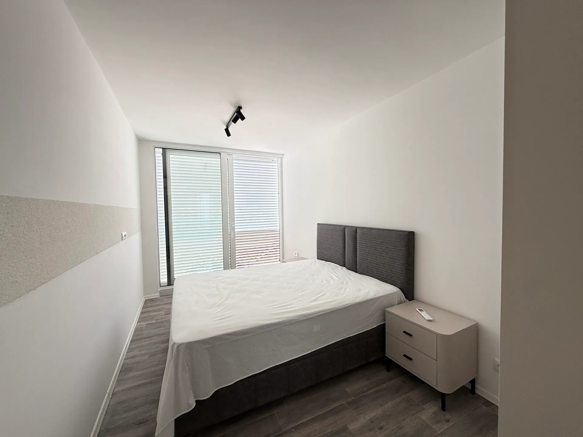 Luştica, Karadağ'daki townhouse'da gri çift kişilik yatak, komodin ve panoramik pencereye sahip modern yatak odası