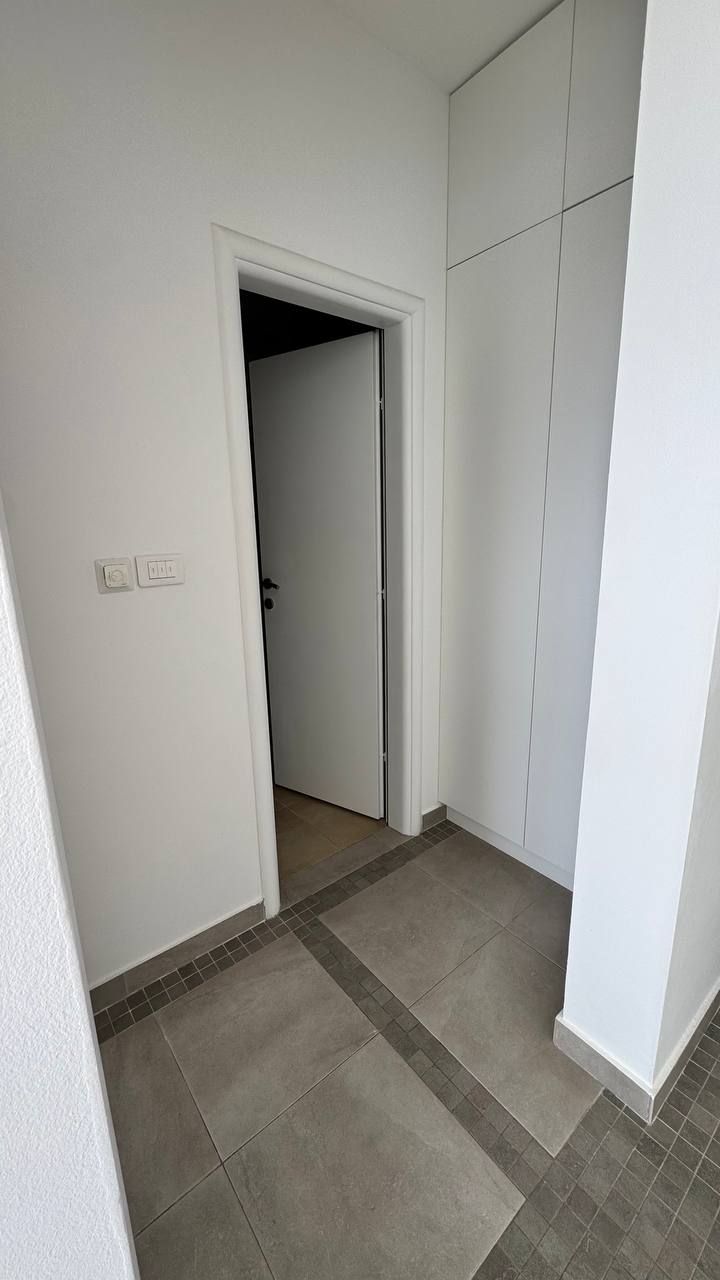 Moderan enterijer hodnika sa belim ugradnim ormarom i porcelanskim pločicama u stanu, Budva, Crna Gora.
