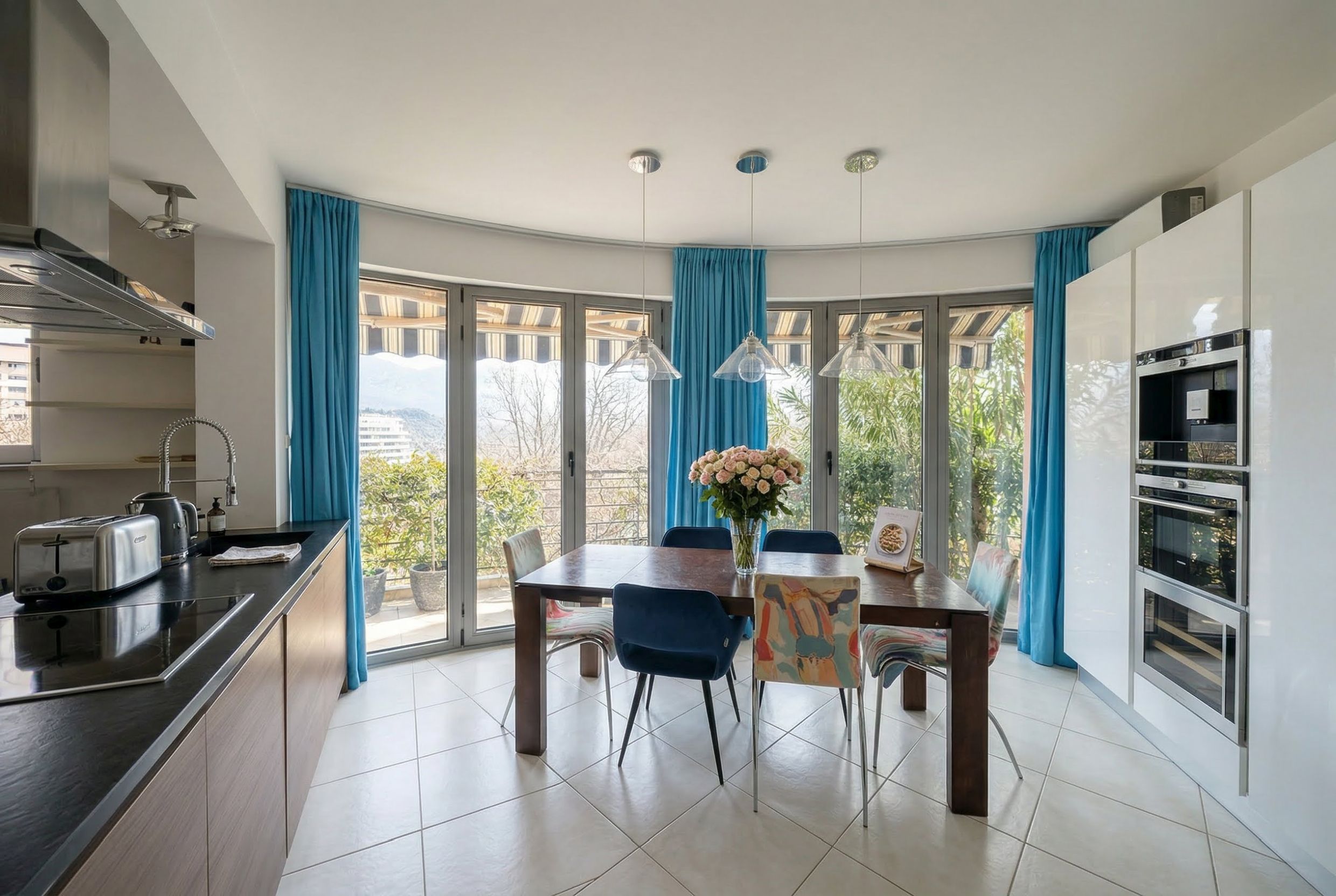 Moderne Wohnküche in einer Wohnung in Bečići, Montenegro: Essbereich mit Panoramafenstern und Zugang zur Terrasse.