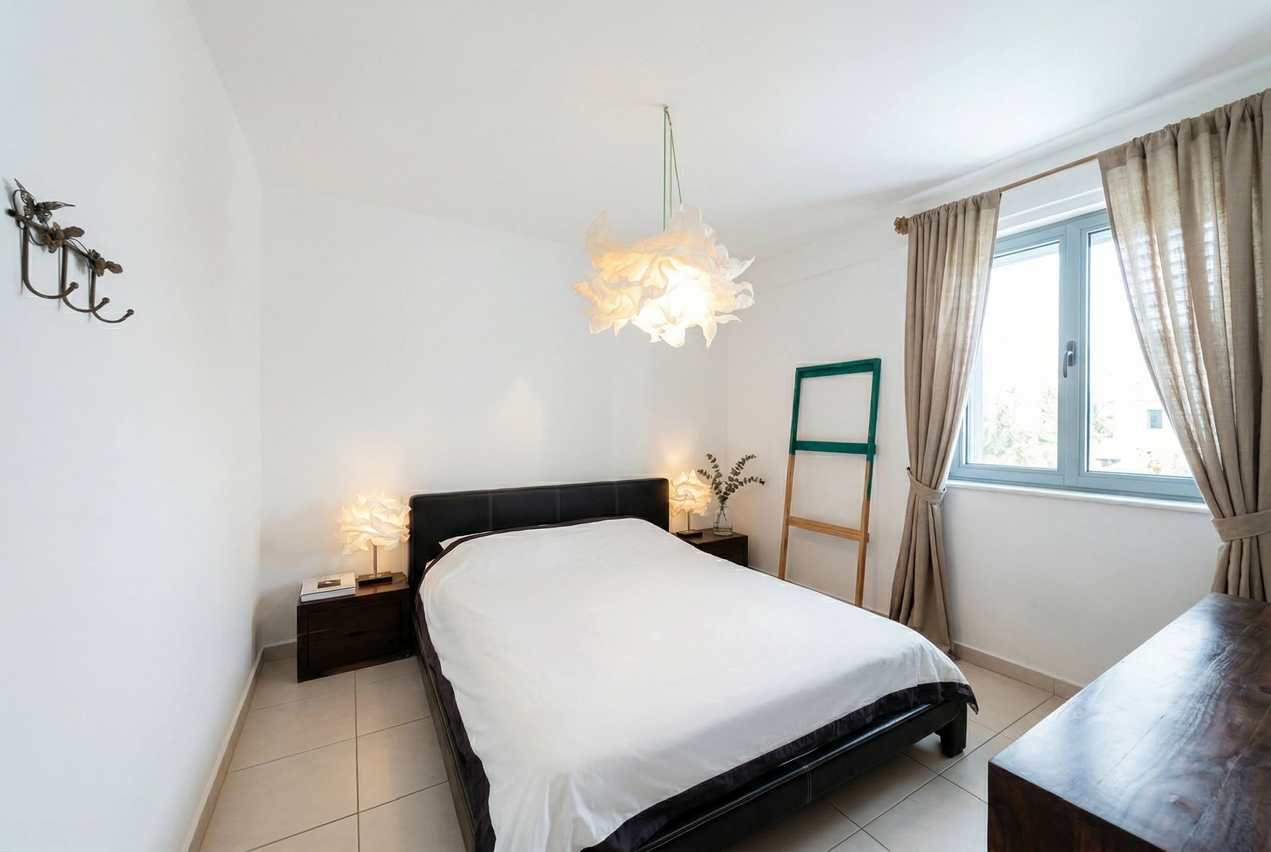 Helles Schlafzimmer in einer Wohnung in Bečići, Montenegro: Doppelbett, Designerleuchten und Fliesenboden.