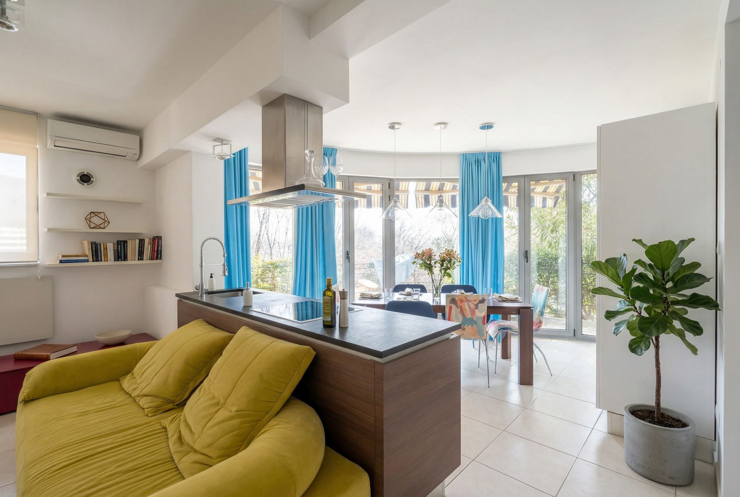 Modernes Wohnzimmer mit Küche in einer Wohnung in Bečići, Montenegro: gelbes Sofa, Essbereich und Panoramafenster.