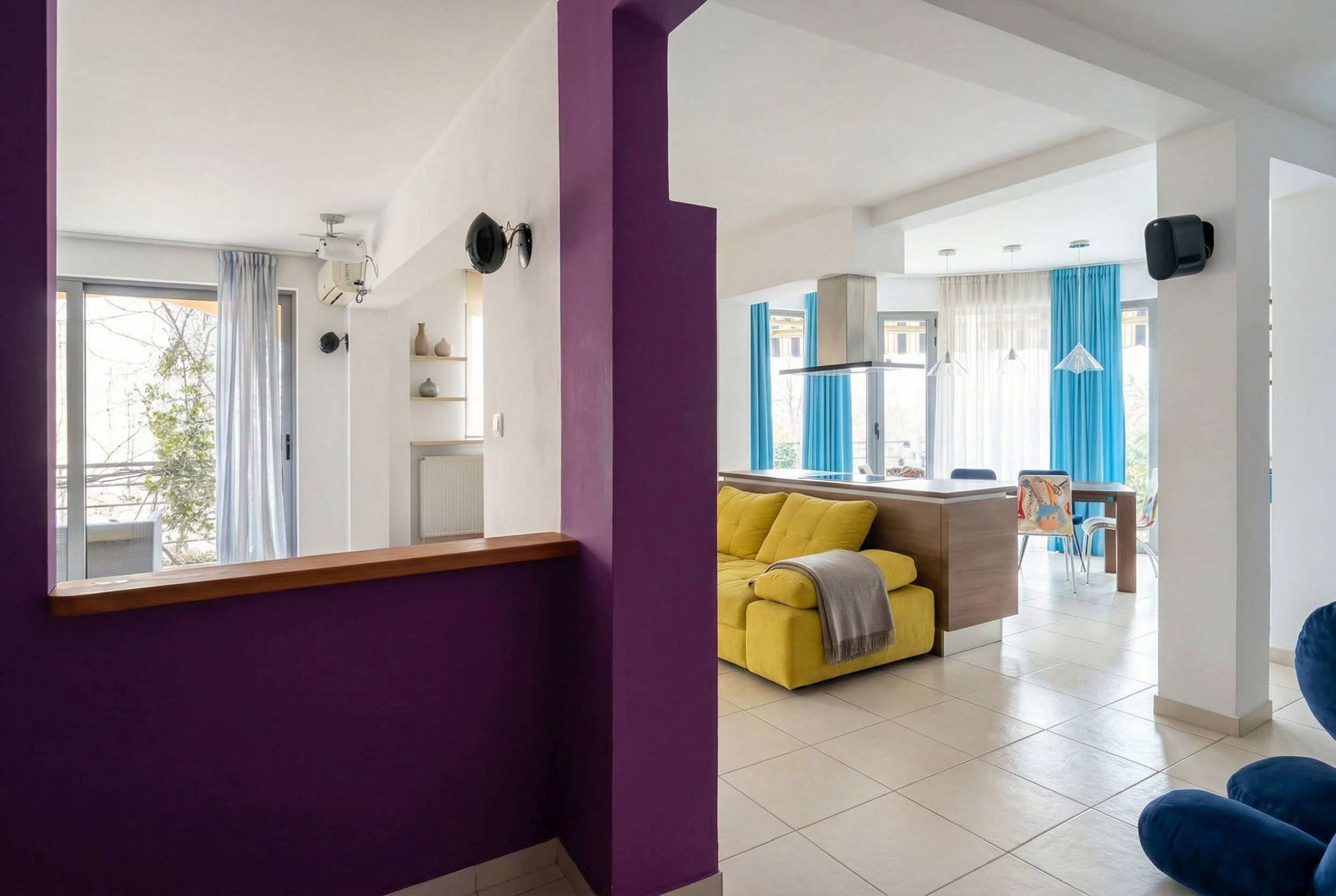 Wohnzimmer mit gelbem Sofa und Küche in einer modernen Wohnung in Bečići, Montenegro. Helles Interieur mit farbigen Akzenten.