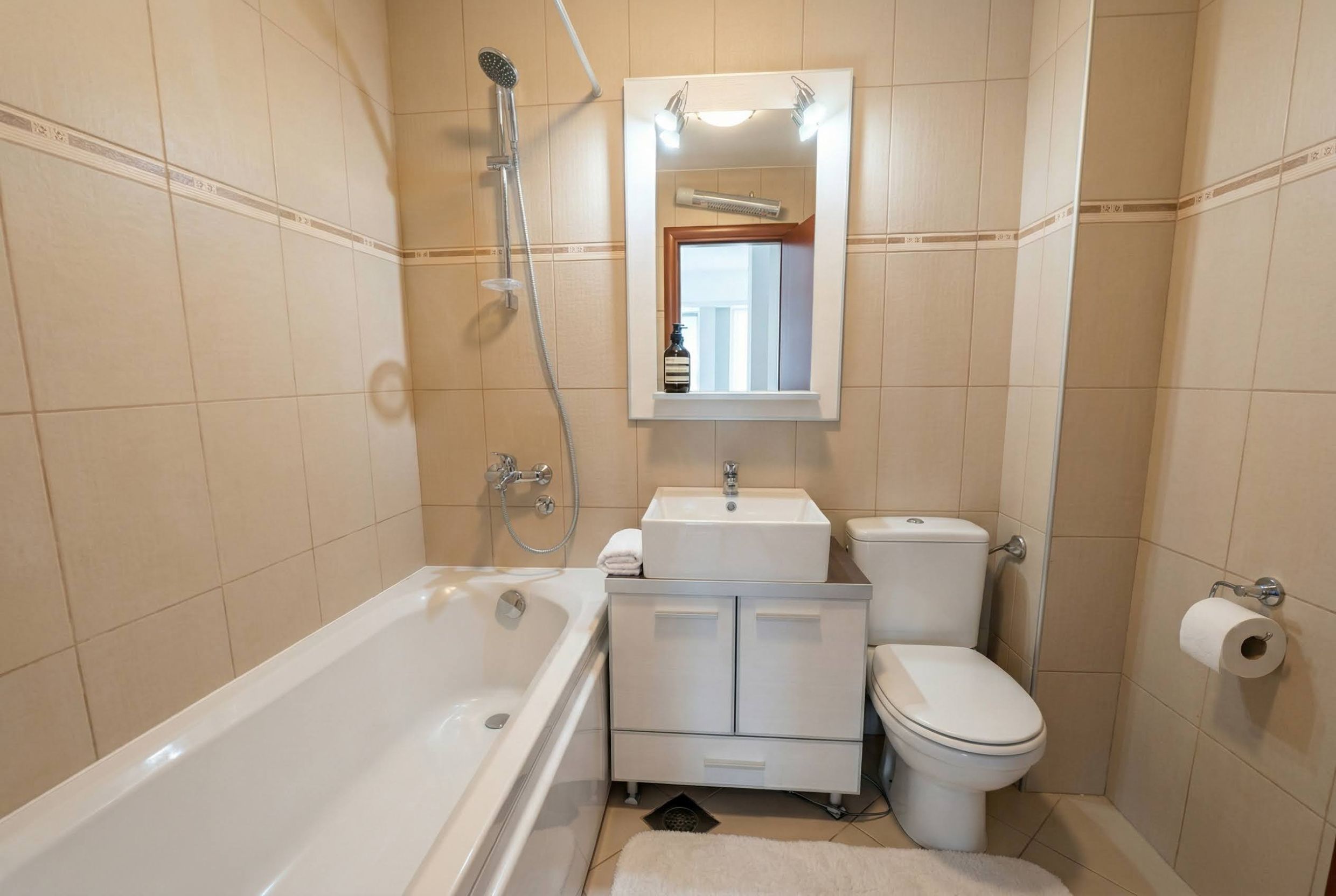 Badezimmer mit weißer Sanitärkeramik und beigen Fliesen in einer Wohnung in Bečići, Montenegro. Modernes Interieur.