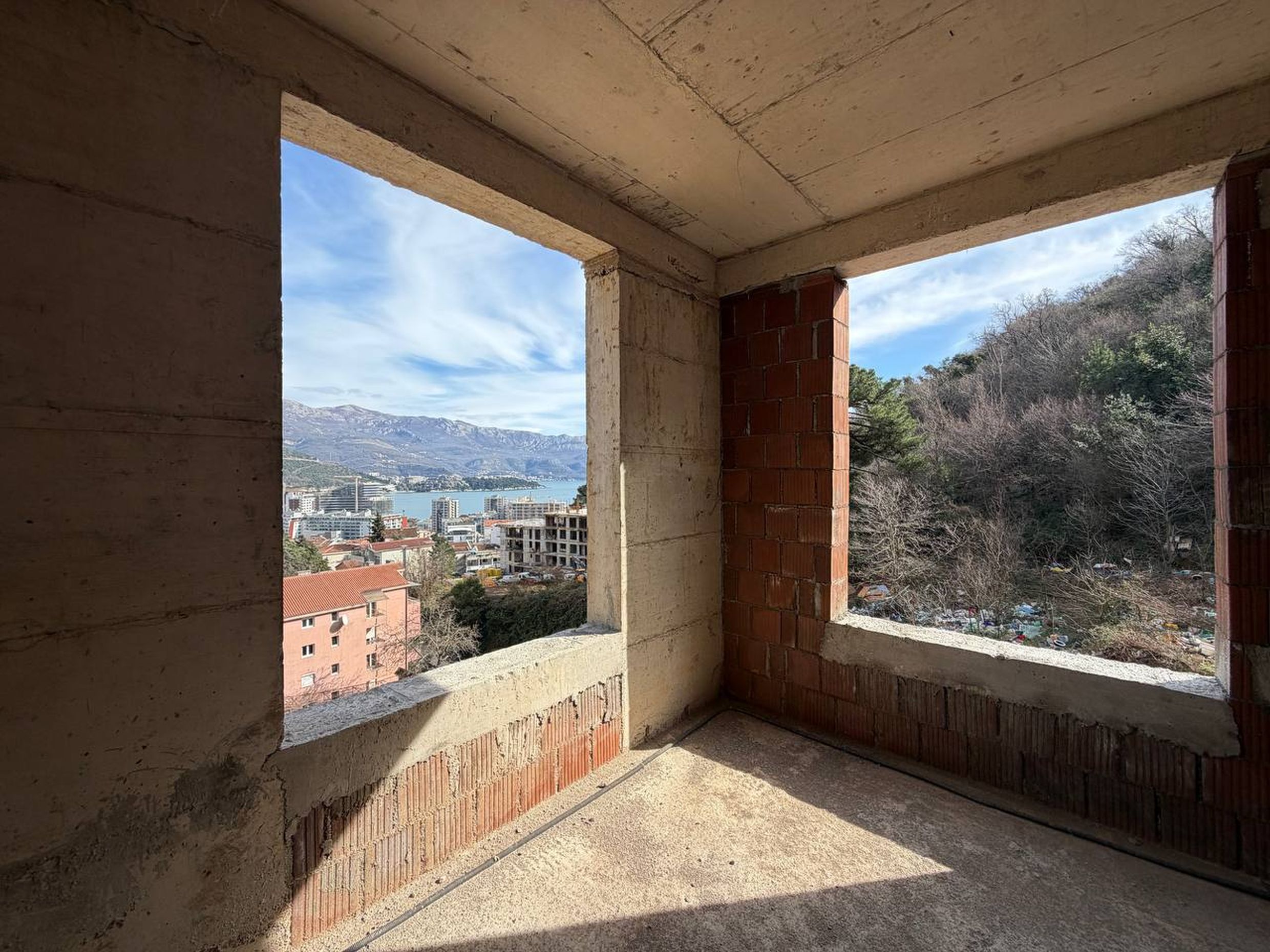 Balkon bez završne obrade u stambenom kompleksu u izgradnji u Budvi, Crna Gora, sa panoramskim pogledom na more i planine.