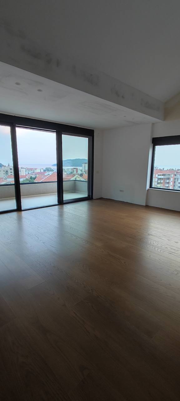 Helles Wohnzimmer in einem Penthouse in Budva, Montenegro: Panoramafenster, Meerblick, Parkettboden und Zugang zur Terrasse.