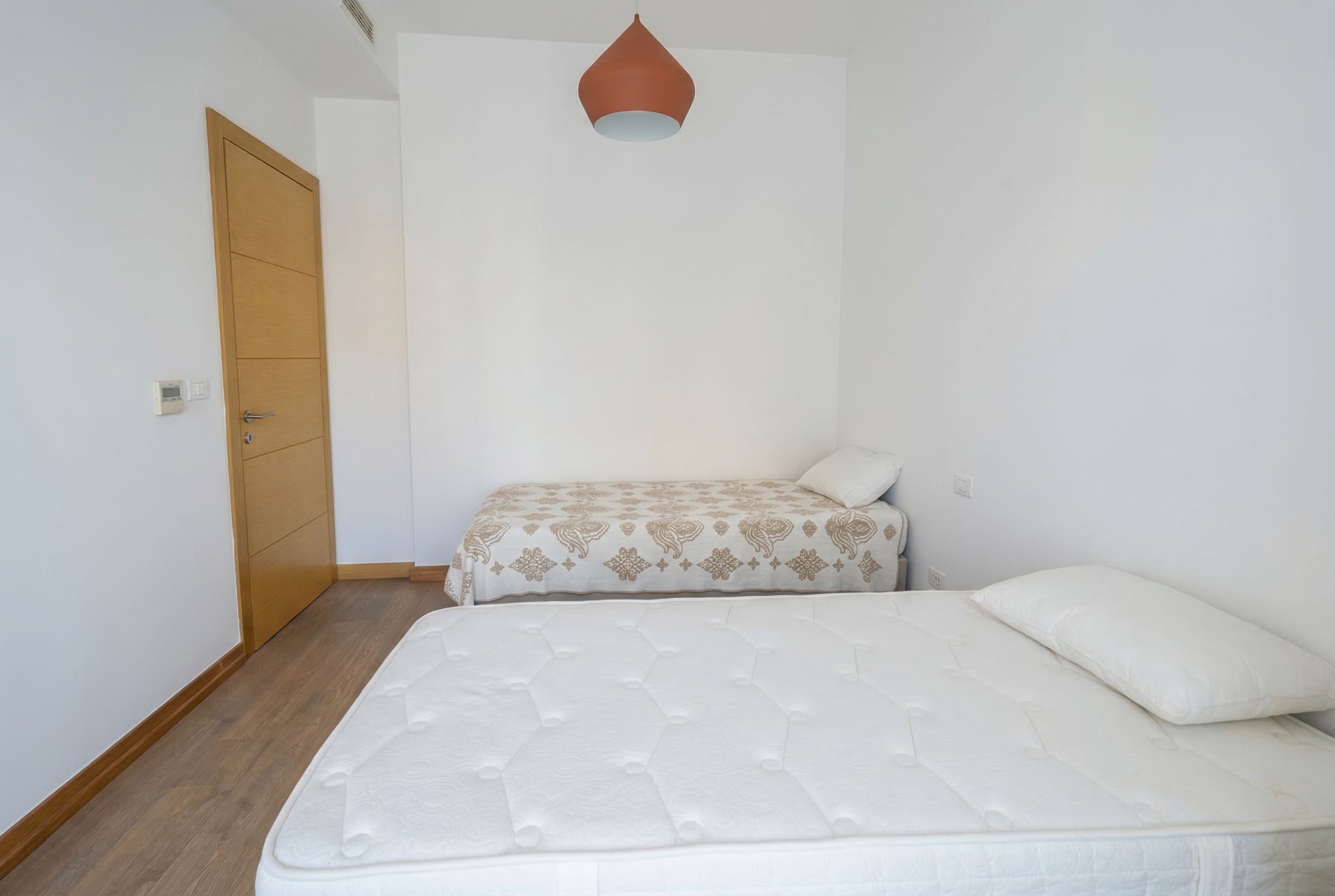 İki yataklı, ahşap zeminli ve modern detaylara sahip aydınlık yatak odası, Budva, Karadağ.