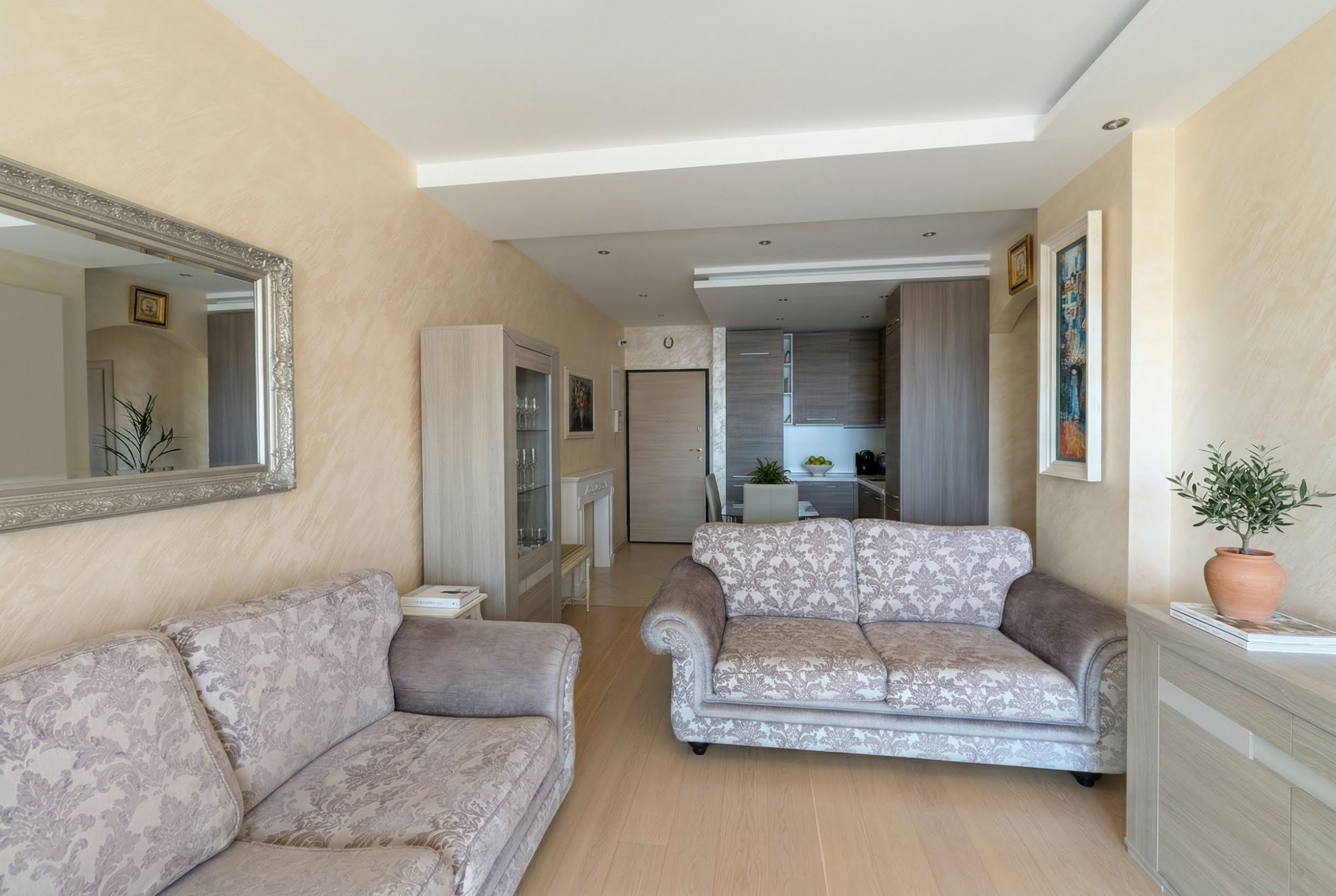 Living room with soft furniture and kitchen in an apartment in Bečići, Montenegro: bright interior, parquet flooring, and modern decor.