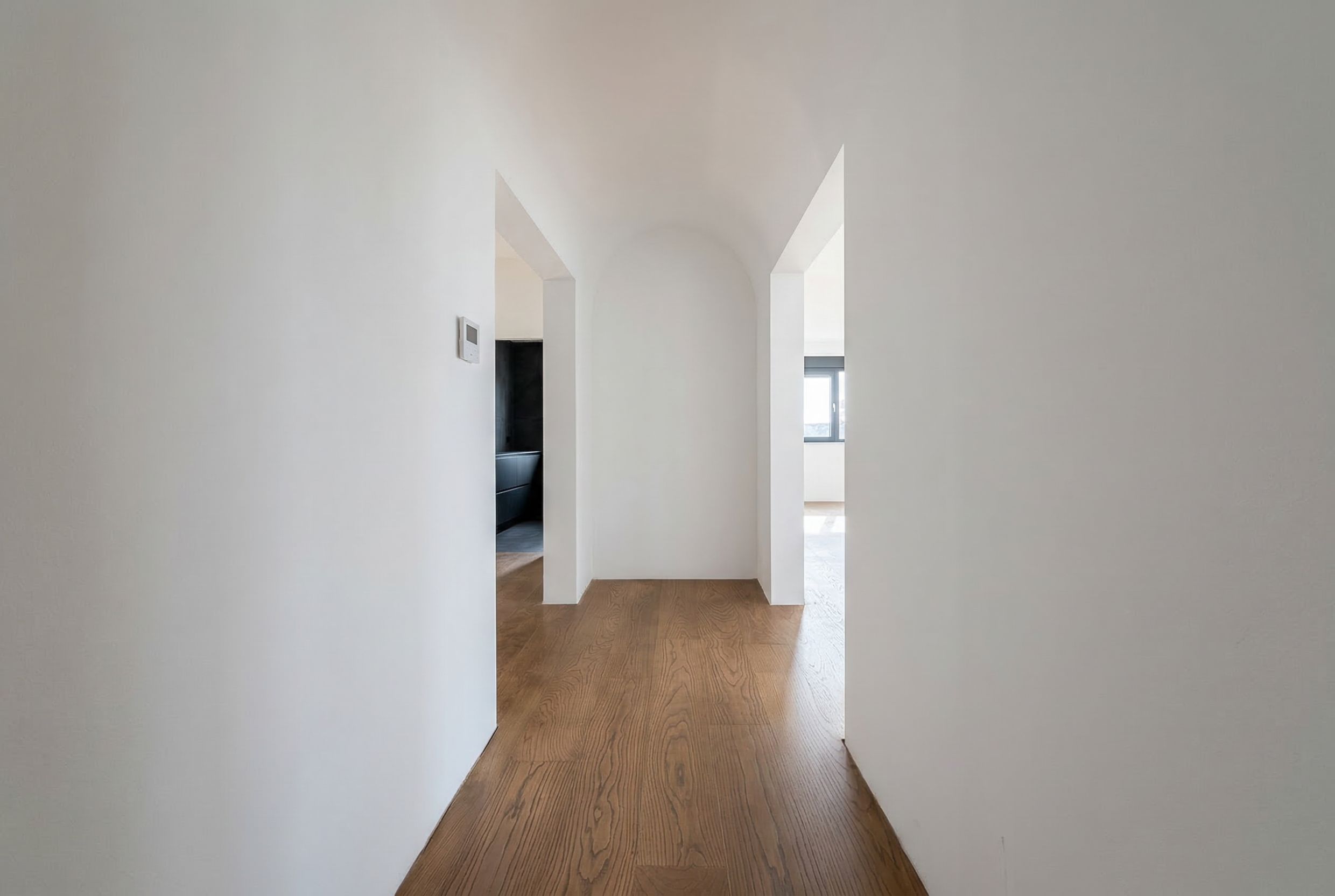 Heller Flur mit Bogendurchgang und Holzboden in einem Penthouse, Budva, Montenegro. Modernes Wohnungsinterieur.