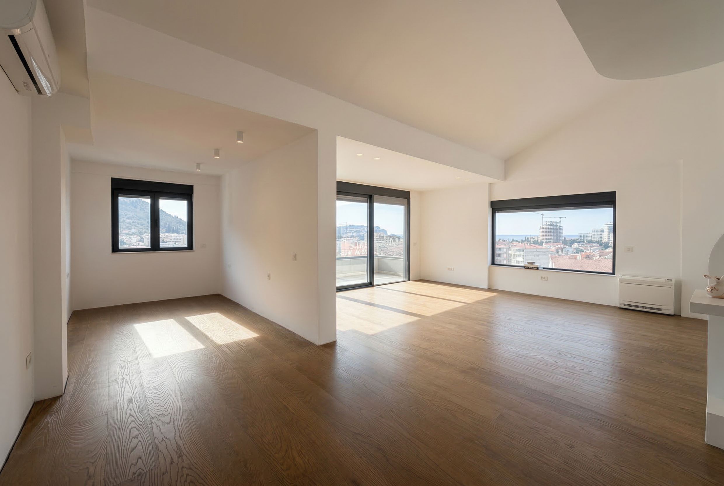 Geräumiges, helles Wohnzimmer in einem Penthouse, Budva, Montenegro: Panoramafenster, Parkettboden und Zugang zur Terrasse.