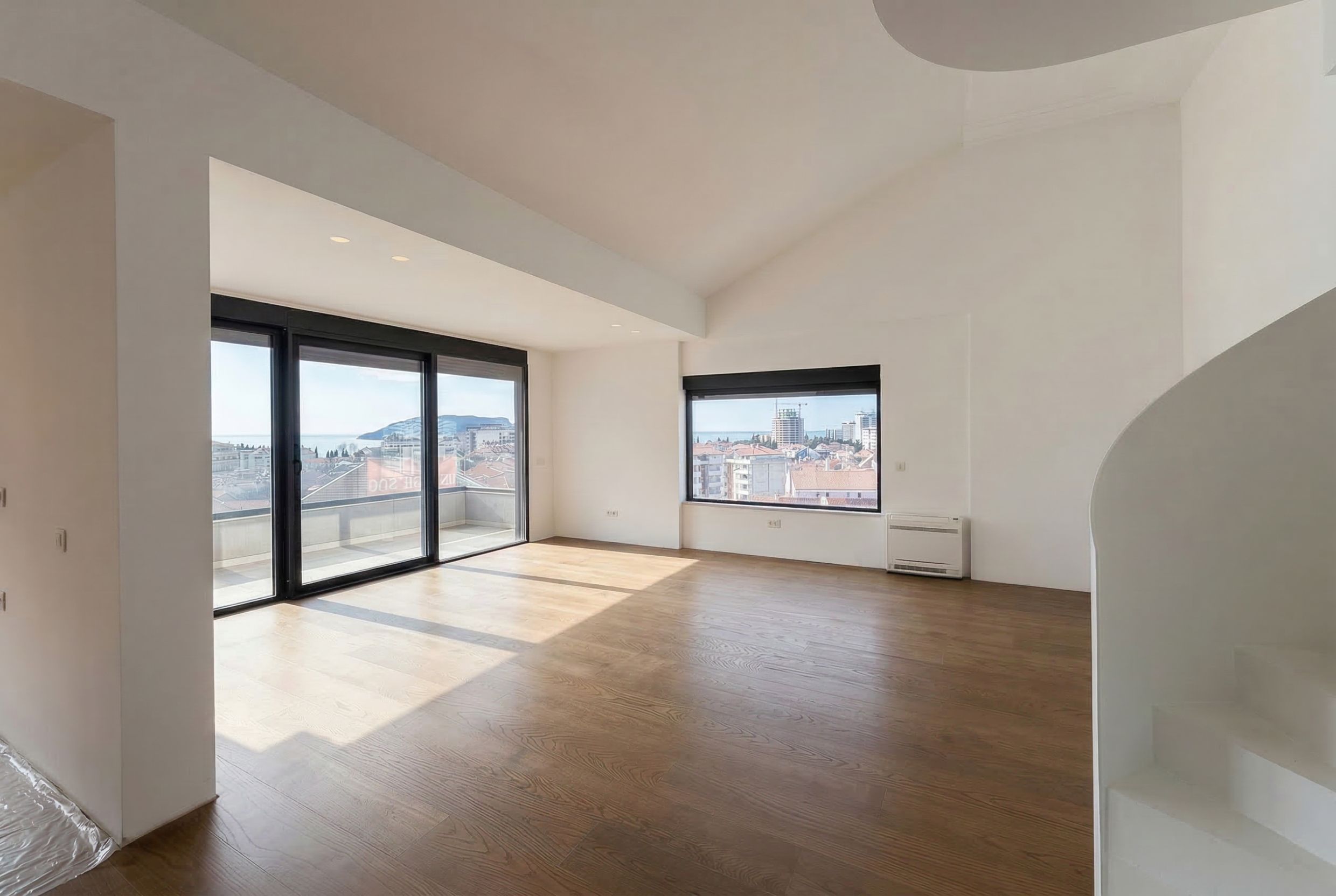 Helles Wohnzimmer in einem Penthouse in Budva, Montenegro: Panoramafenster, Meerblick, Holzboden und Treppe.