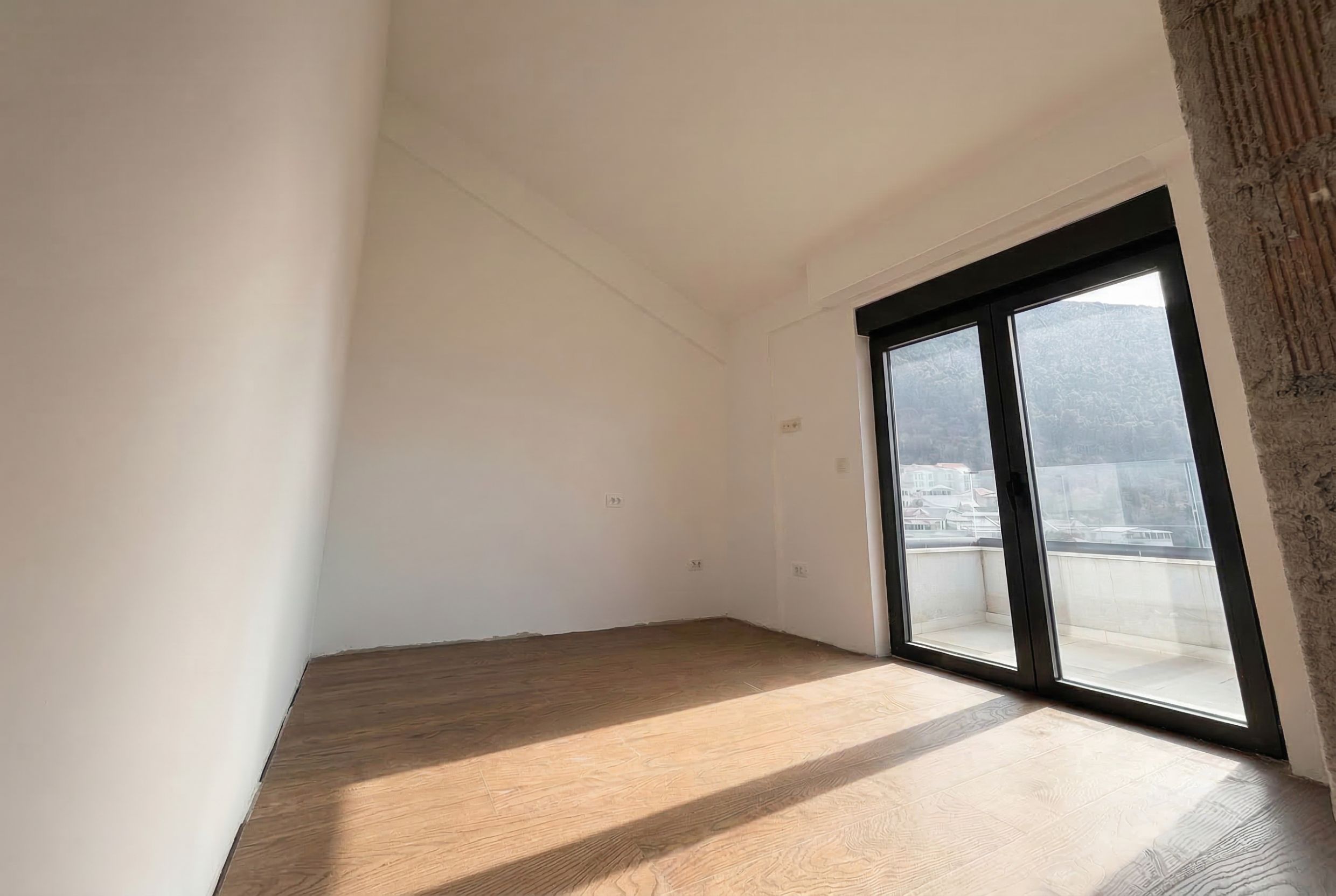 Helles Schlafzimmer in einem Penthouse in Budva, Montenegro: Panoramafenster, Zugang zur Terrasse, bezugsfertiger Ausbau, Bergblick.