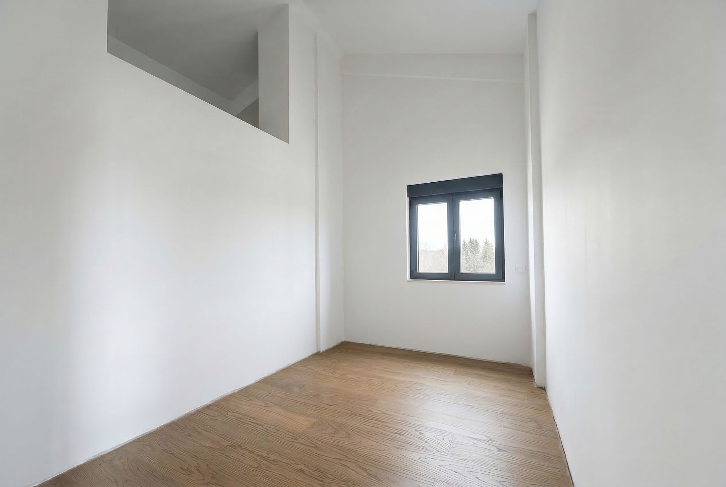 Helles Schlafzimmer mit hohen Decken und Parkettboden in einem Penthouse, Budva, Montenegro. Moderne Ausstattung, Blick aus dem Fenster.