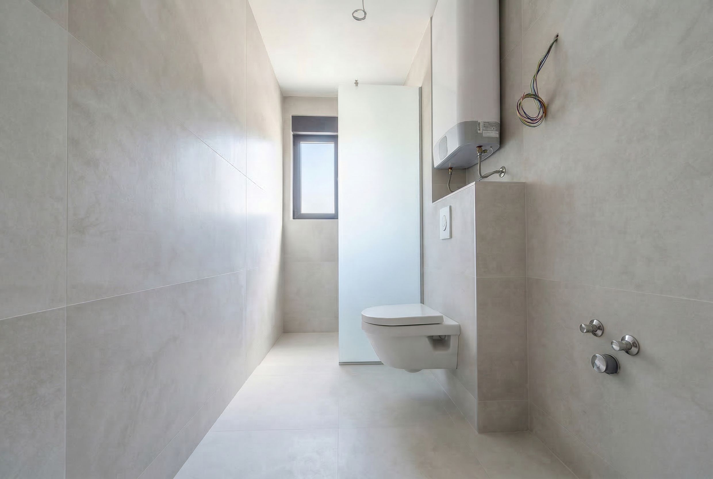 Modernes Badezimmer in einem Penthouse in Budva, Montenegro: helle Fliesen, wandhängendes WC und Boiler.