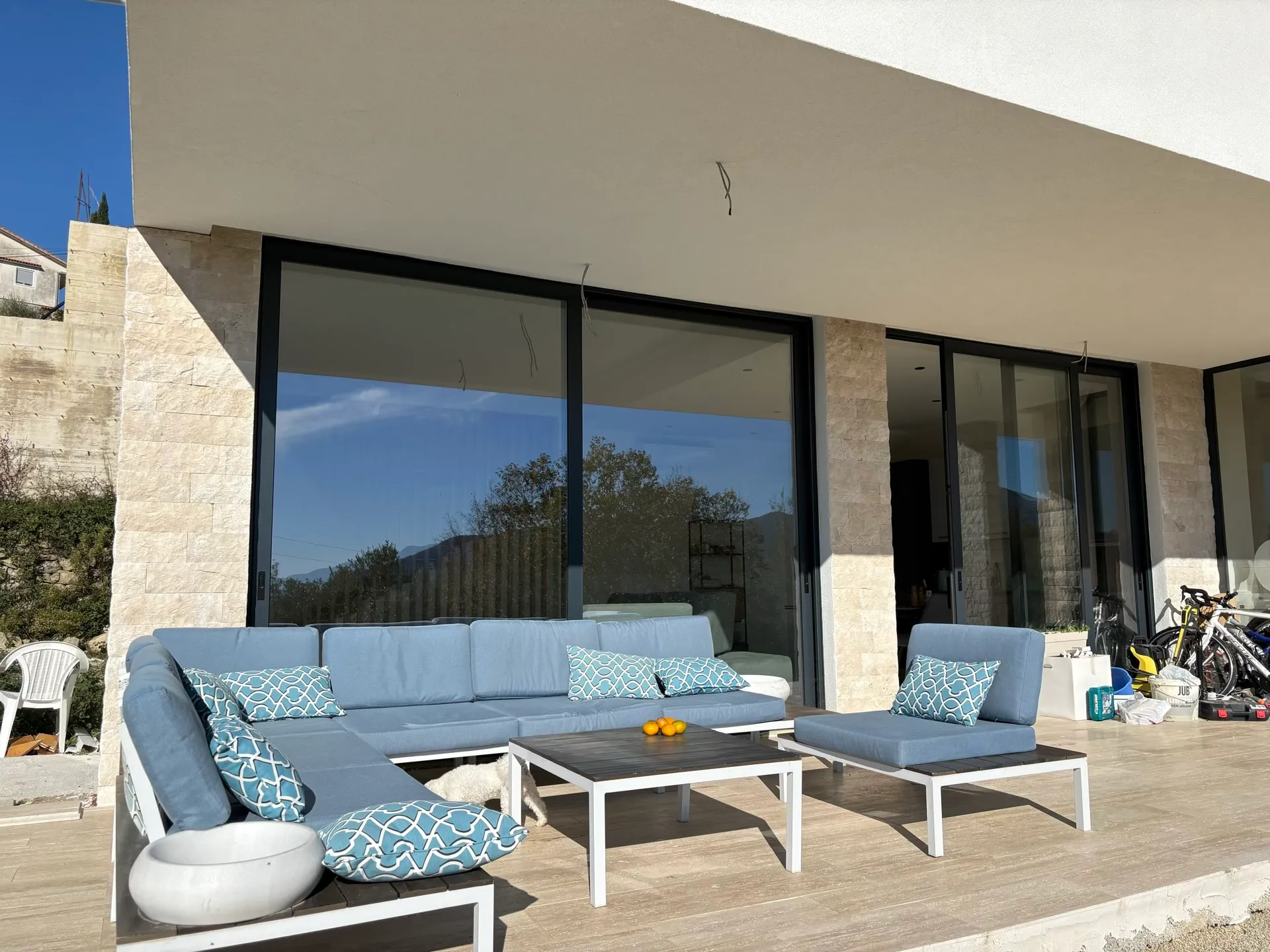 Terrace of a modern villa in Herceg Novi, Montenegro: blue upholstered furniture, panoramic glazing, and stone finishes.