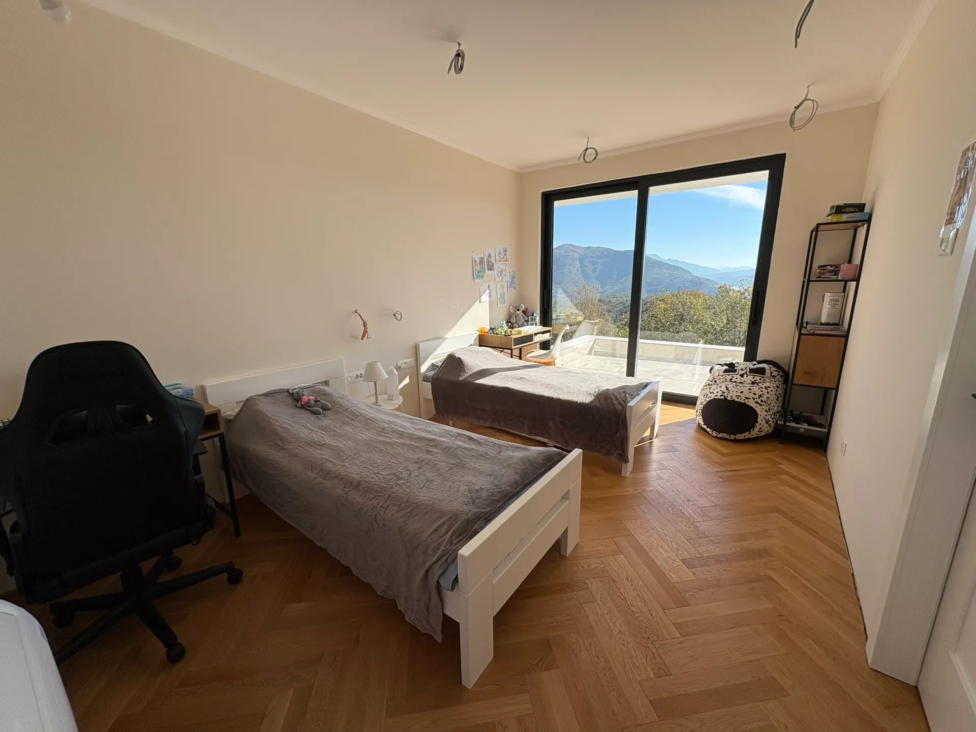 Children's bedroom with two beds, parquet flooring, and panoramic mountain views in the Herceg Novi residential complex, Montenegro.