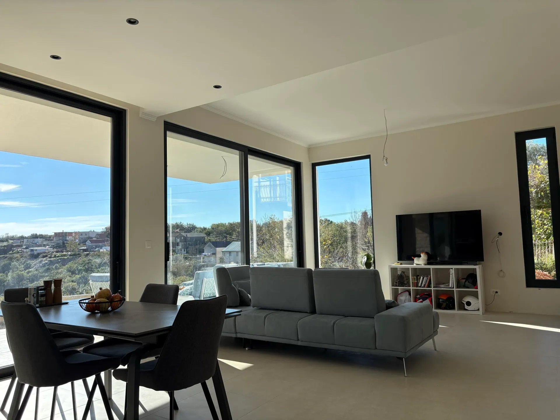Modern living room with panoramic windows and a view of Herceg Novi, Montenegro: stylish furniture and a bright interior.