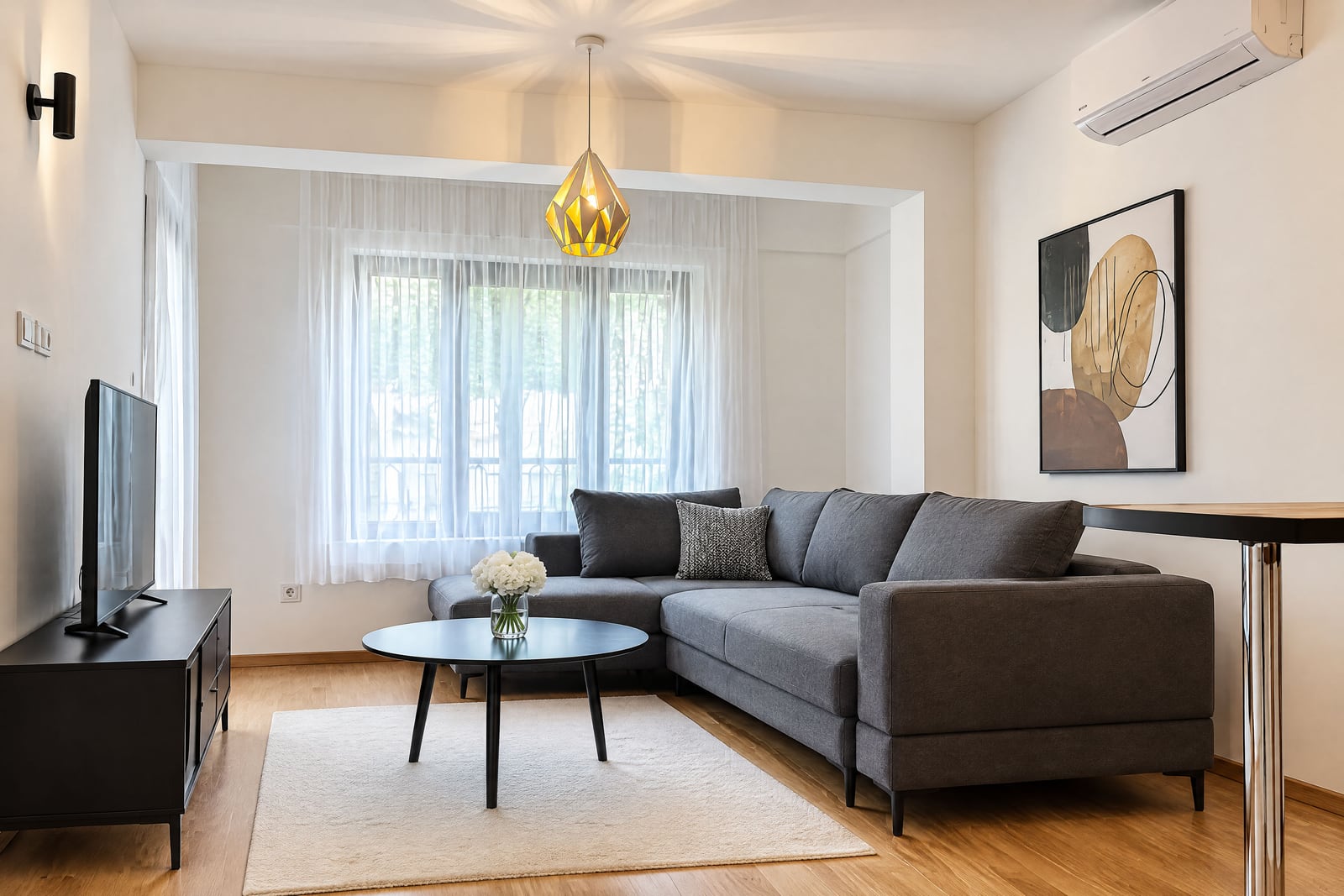 Modern living room with a gray corner sofa and TV in an apartment in Budva, Montenegro