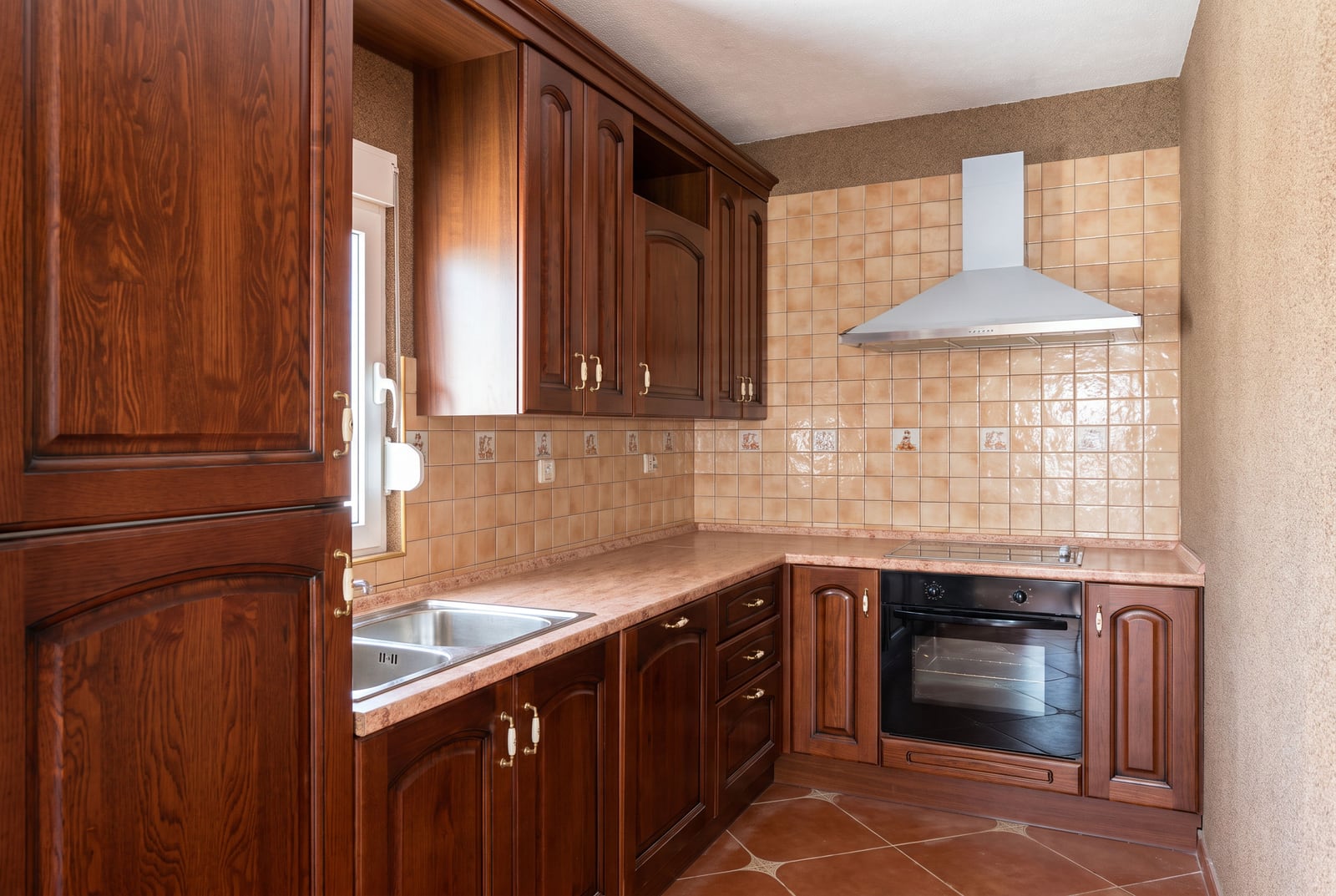 Kitchen with dark wooden furniture, built-in appliances, and tiling in a house in Tivat, Montenegro