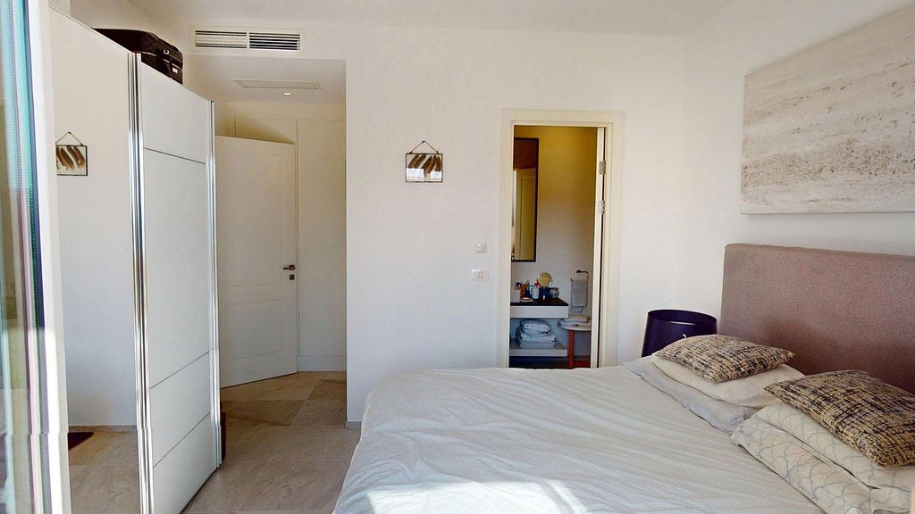 Svetla spavaća soba sa bračnim krevetom i ugradbenim ormarom u apartmanima Luštica, Crna Gora.