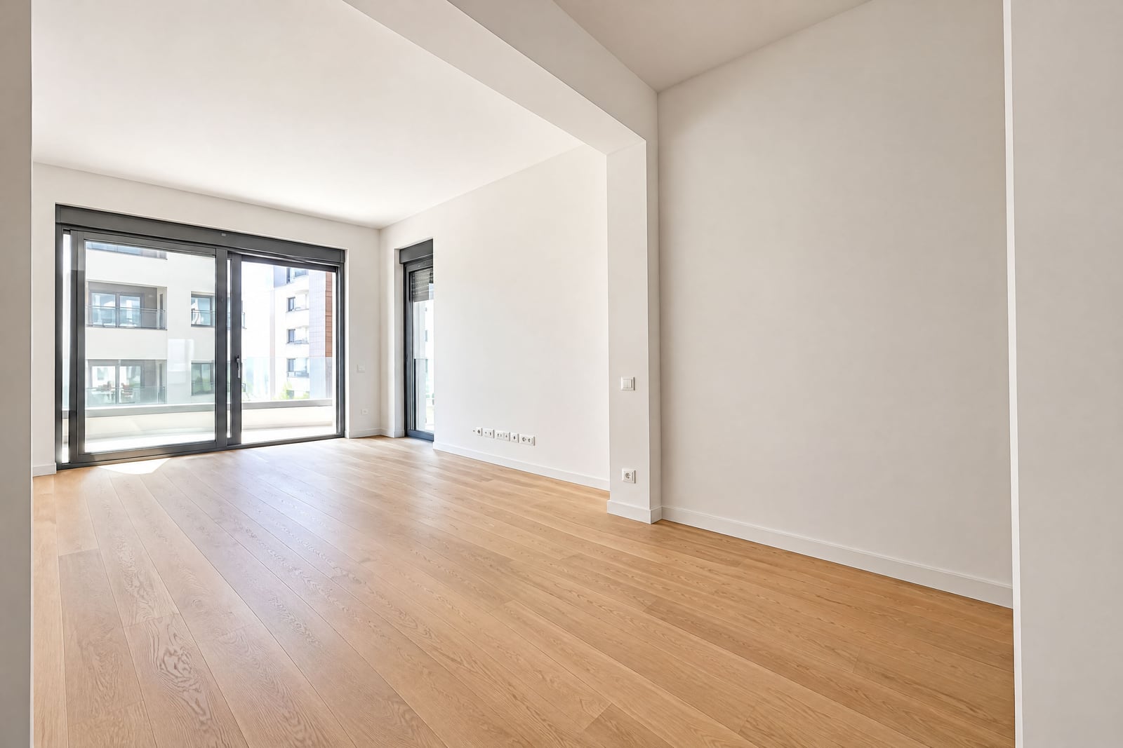 Bright empty living room with panoramic windows and parquet flooring in a new apartment in Becici, Montenegro
