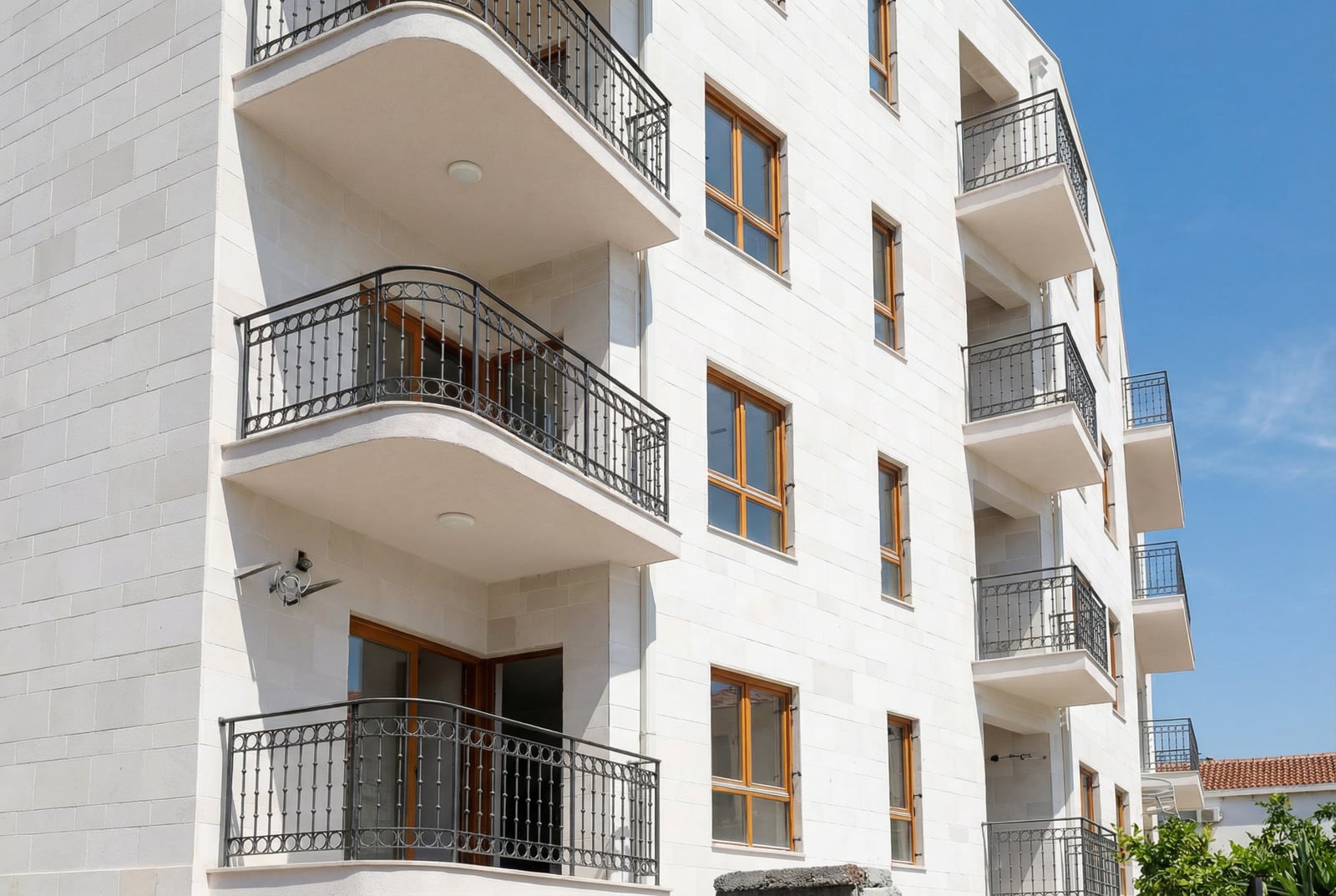 Facade of a modern residential building with balconies and stone cladding in Petrovac, Montenegro.