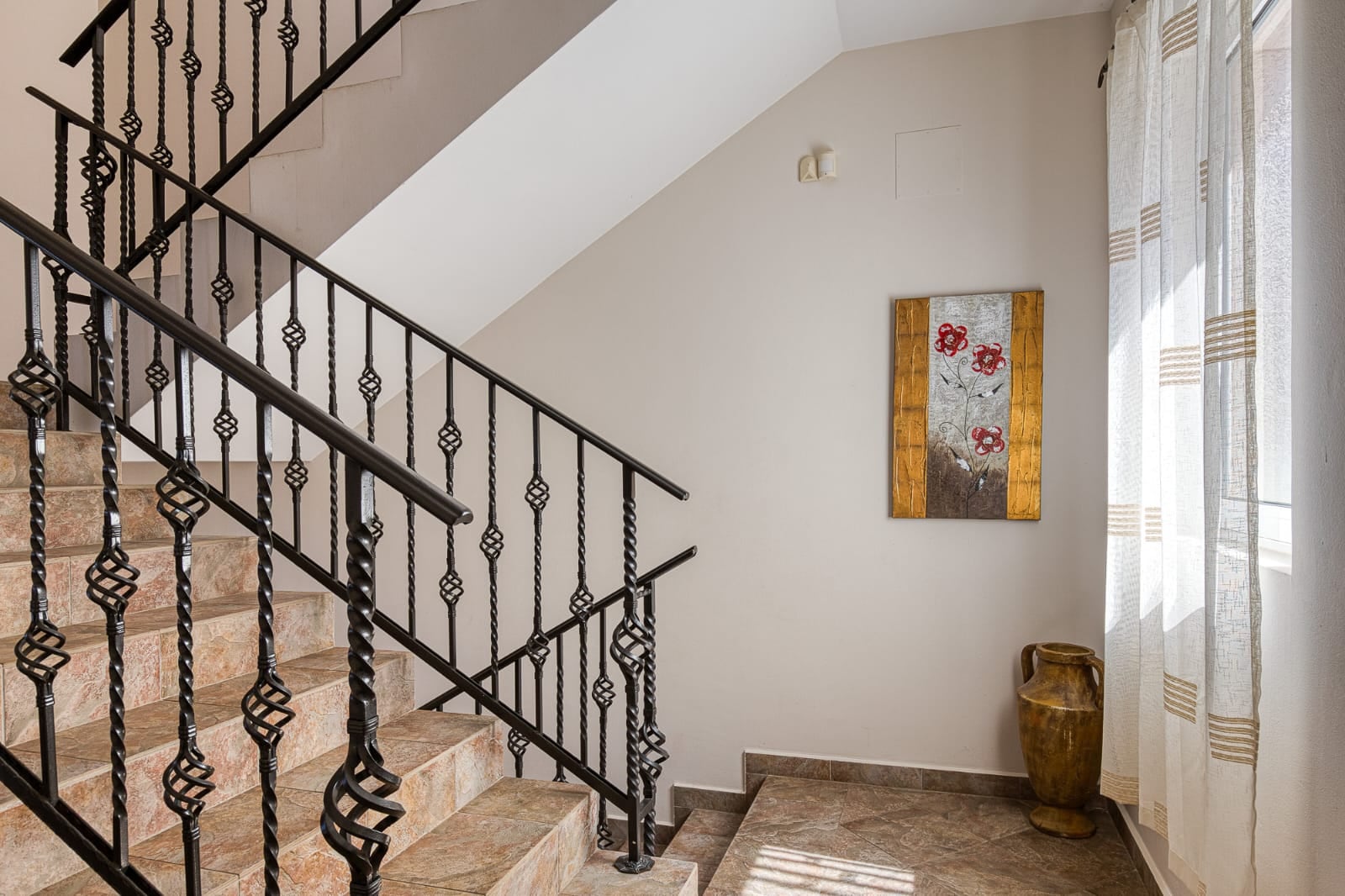 Escalier avec rampe en fer forgé et carrelage en céramique à l'intérieur d'une villa à Bečići, Monténégro.