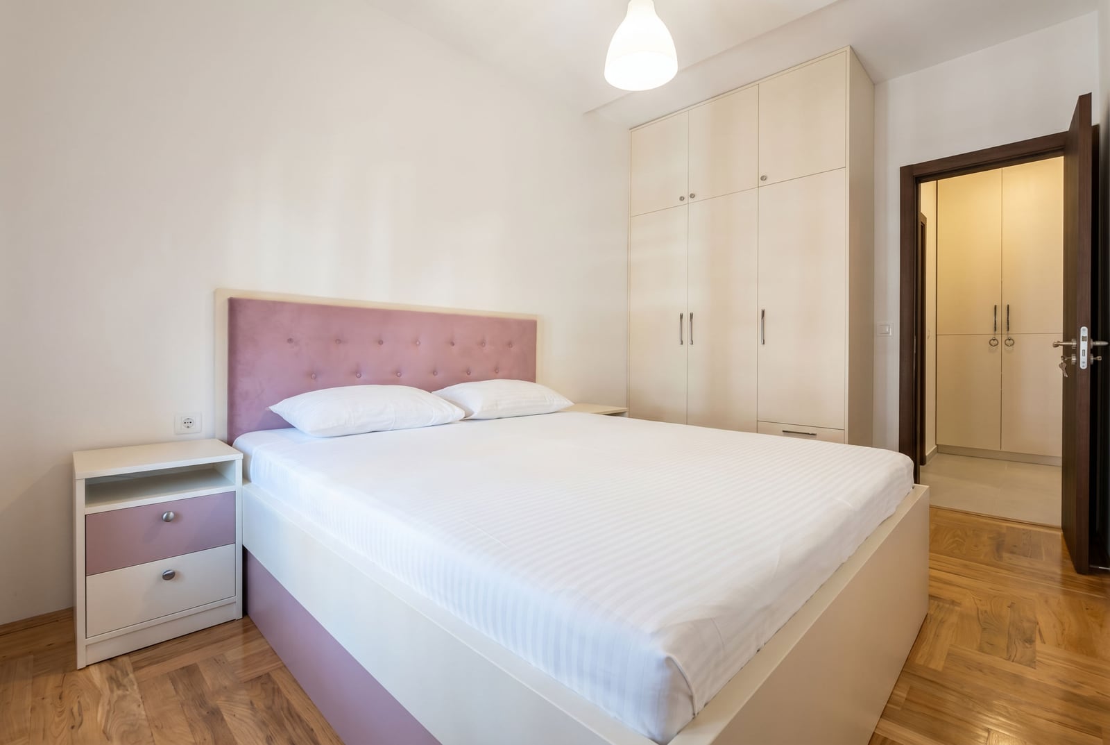 Jasna sypialnia z łóżkiem małżeńskim i szafą wnękową w apartamencie, Rafailovići, Czarnogóra.