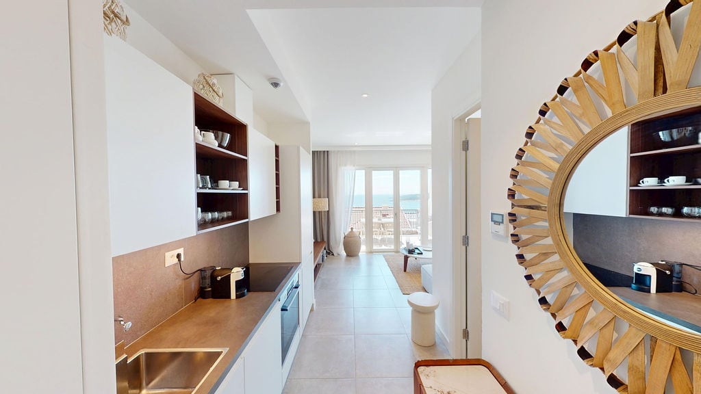Moderne Küche in einer Wohnung, Luštica, Montenegro: helles Interieur, eingebaute Geräte und Meerblick aus dem Wohnzimmer.