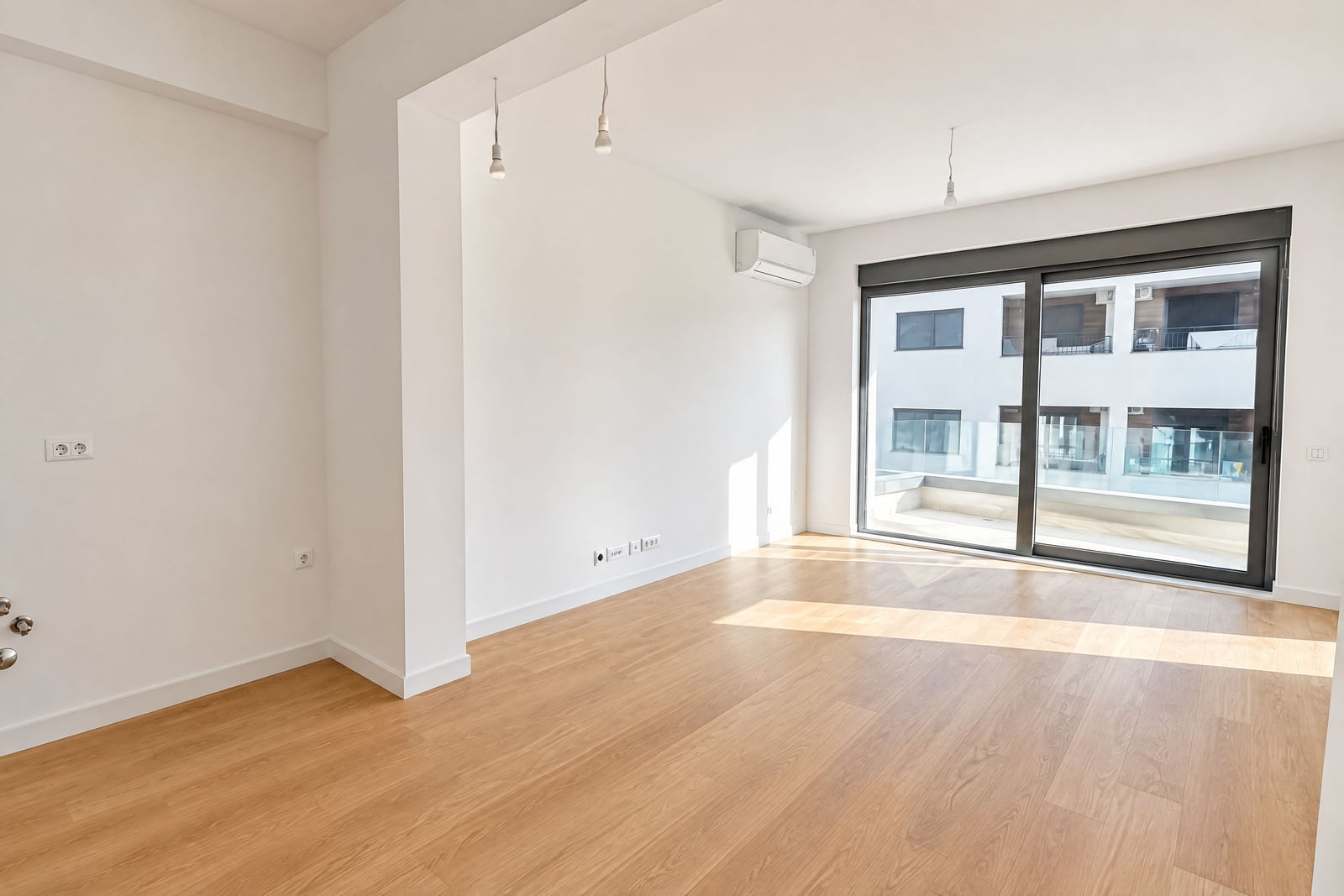 Salon lumineux et vide avec une fenêtre panoramique et un parquet dans un appartement neuf à Bečići, Monténégro