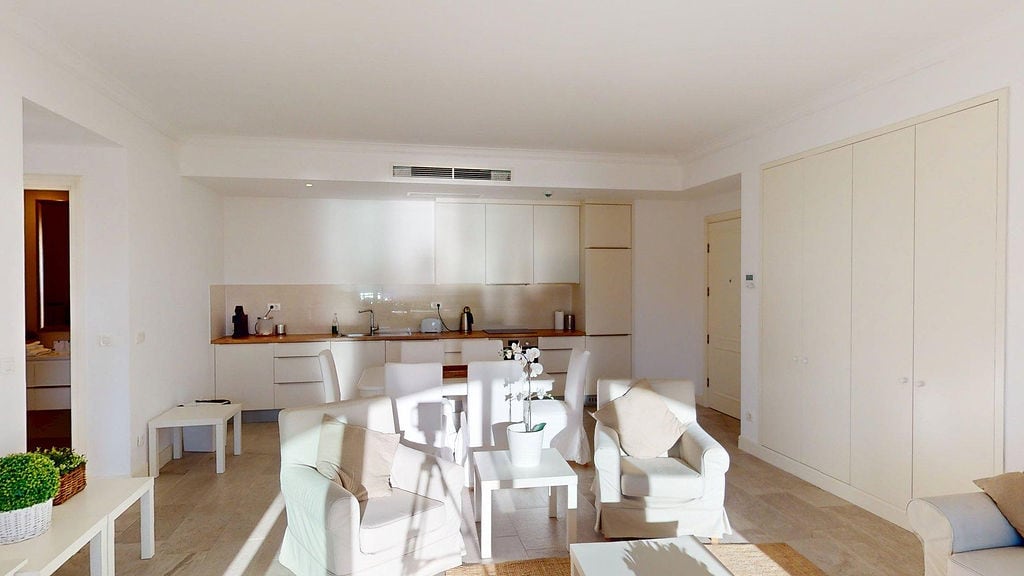 Helles Wohnzimmer mit Küche im modernen Stil in der Apartmentsiedlung Luštica, Montenegro: weiße Möbel und Einbauschränke.