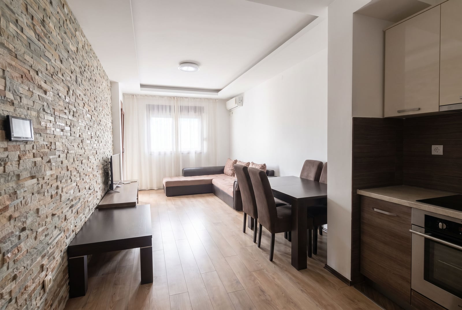 Modernes Wohnzimmer mit Steinwand und Küche in einer Wohnung in Budva, Montenegro