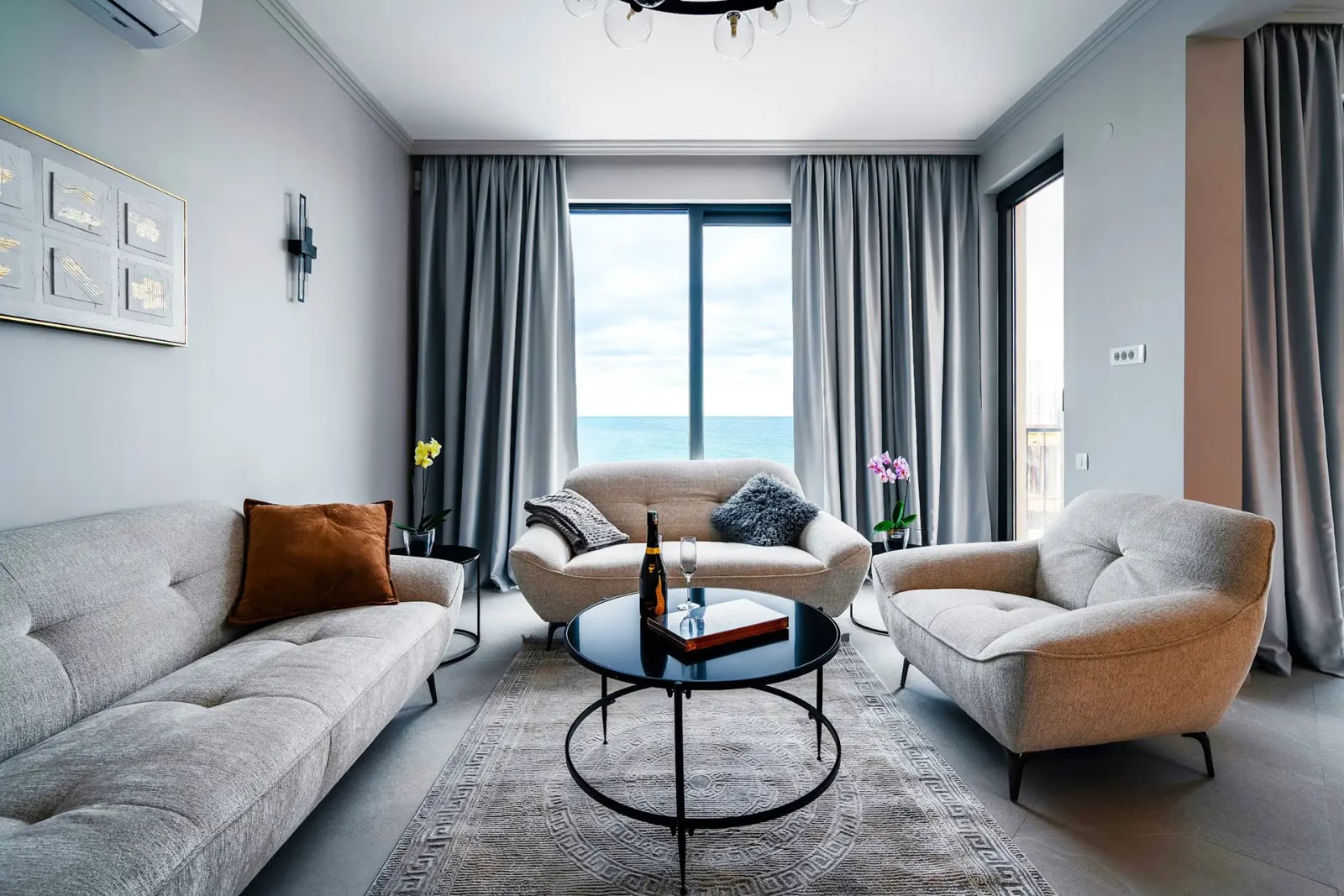 Modern living room with a sea view in a villa in Reževići, Montenegro: light-colored furniture, panoramic windows, and stylish decor.