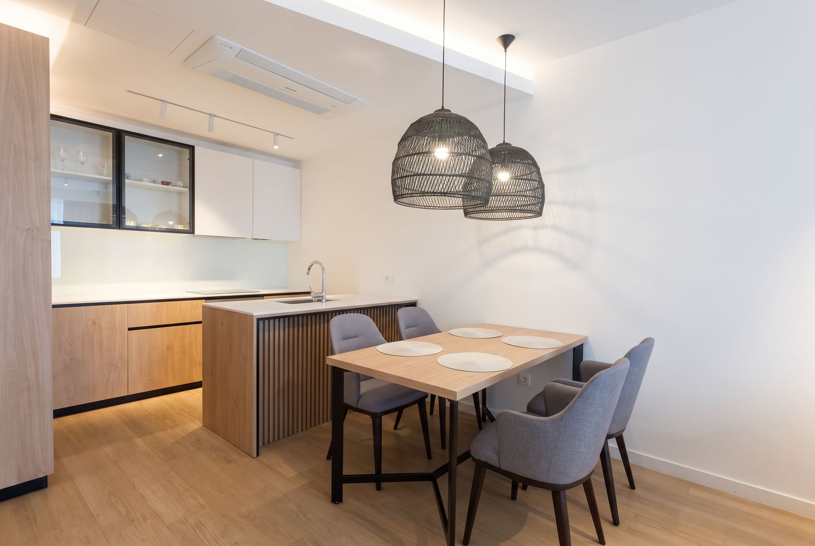 Modern kitchen with wooden cabinetry, an island, and a dining area in an apartment in Budva, Montenegro