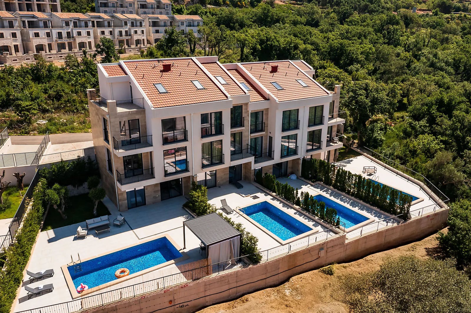 Modern villa in Reževići, Montenegro: three-story house with private pools, terraces, and a view of the green forest.