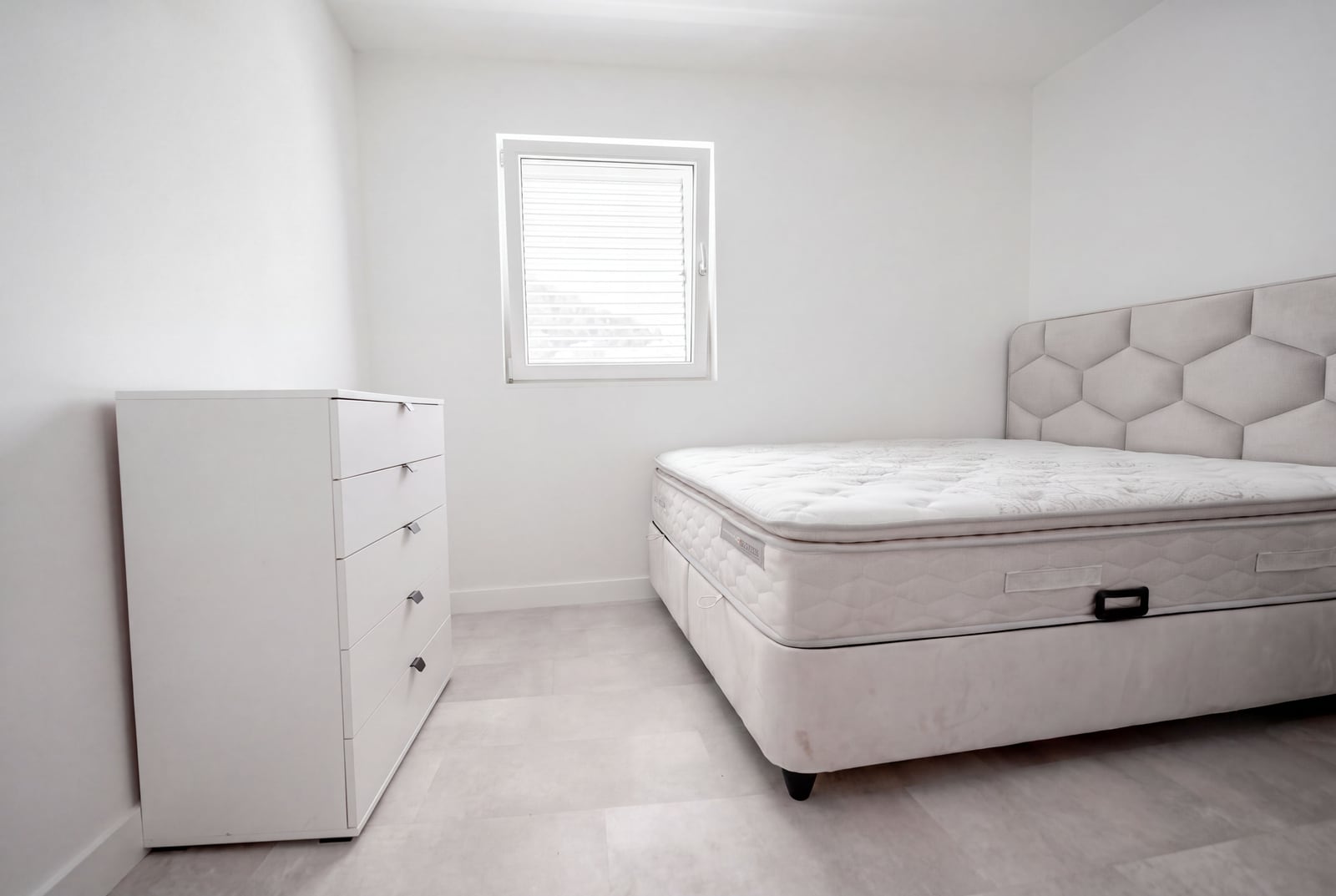 Bright bedroom with a double bed and white dresser in an apartment, Sveti Stefan, Montenegro. Modern interior.
