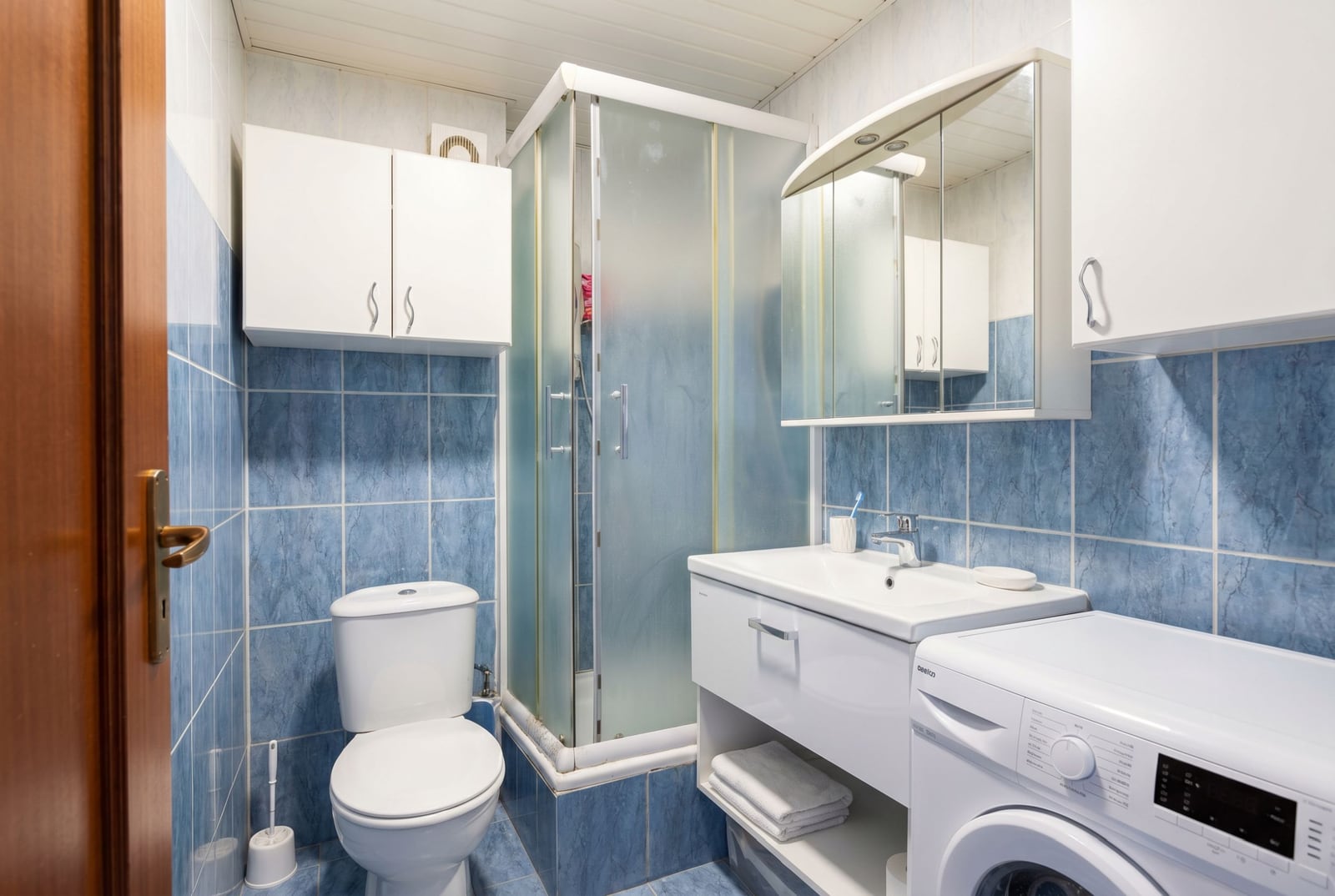 Bathroom in an apartment in Budva, Montenegro: shower cabin, vanity unit with sink, mirror, and washing machine.