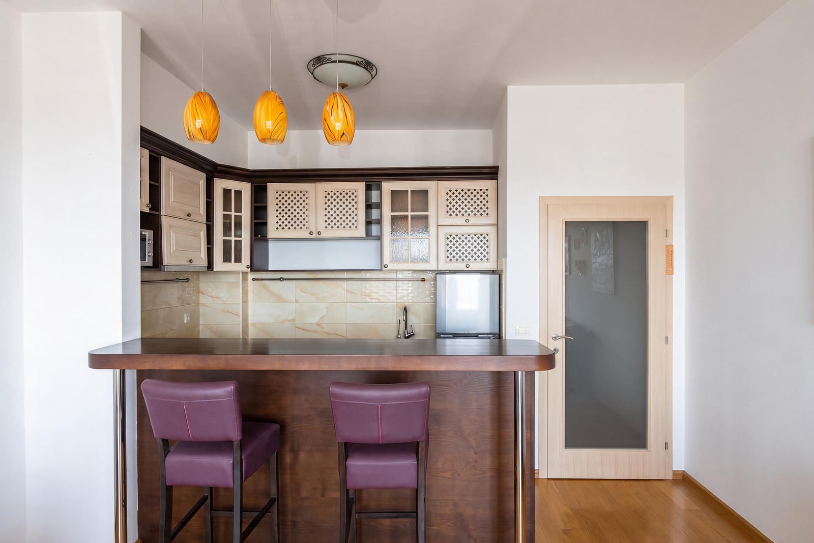 Modern kitchen with a bar counter, purple chairs, and furniture in an apartment in Bečići, Montenegro.
