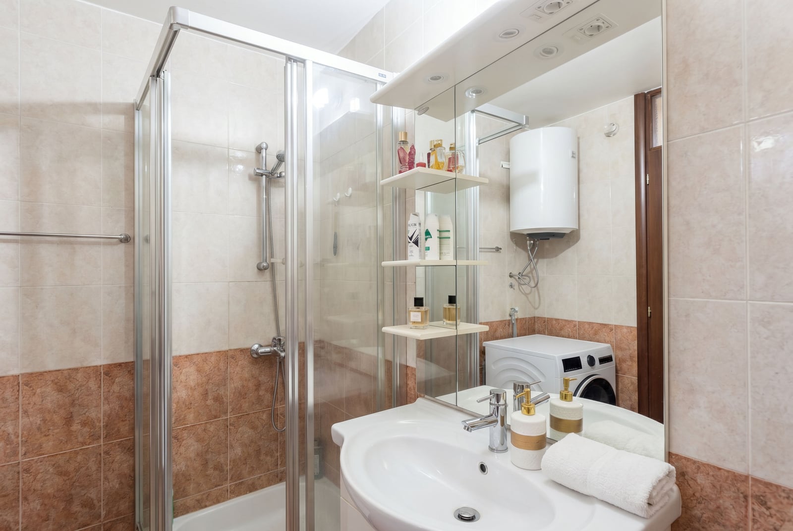 Bathroom in an apartment in Budva, Montenegro: shower cabin, sink, mirror, and washing machine in the interior.