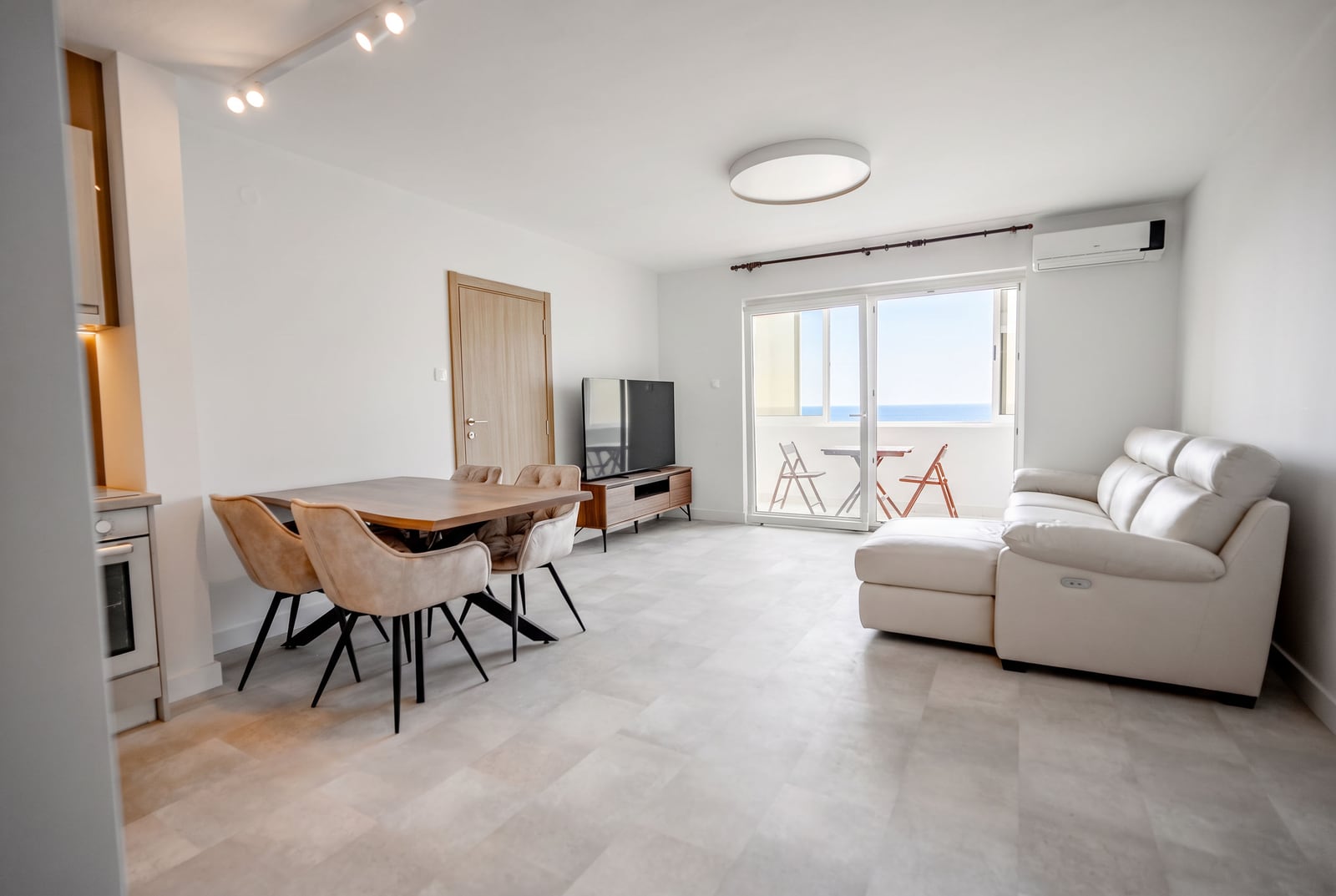 Living room with a white sofa and sea view in an apartment, Sveti Stefan, Montenegro: modern interior and dining area.