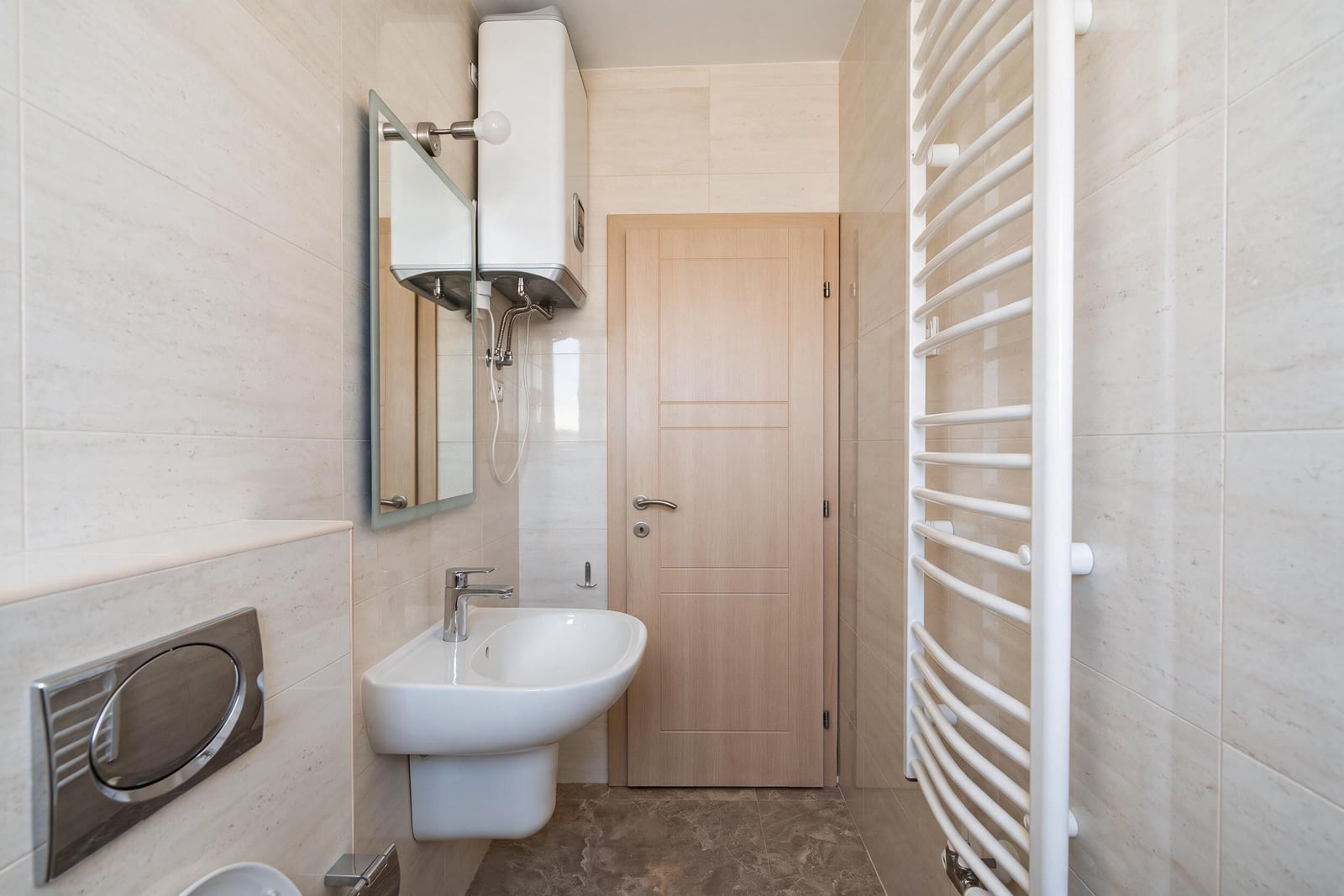 Modern bathroom with a sink, water heater, and towel warmer in an apartment in Bečići, Montenegro.