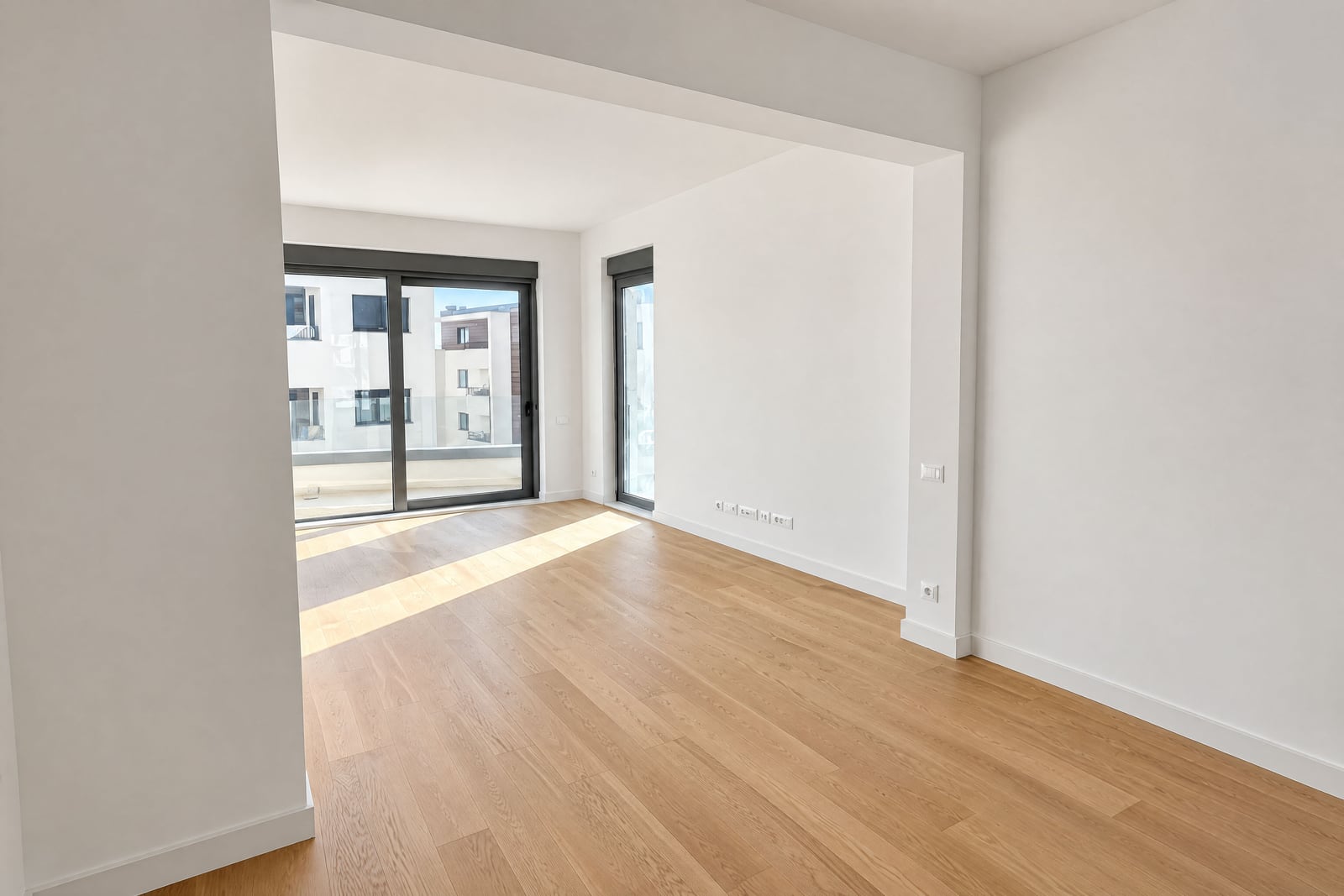 Salon lumineux et vide avec une fenêtre panoramique et un parquet dans un appartement à Bečići, Monténégro